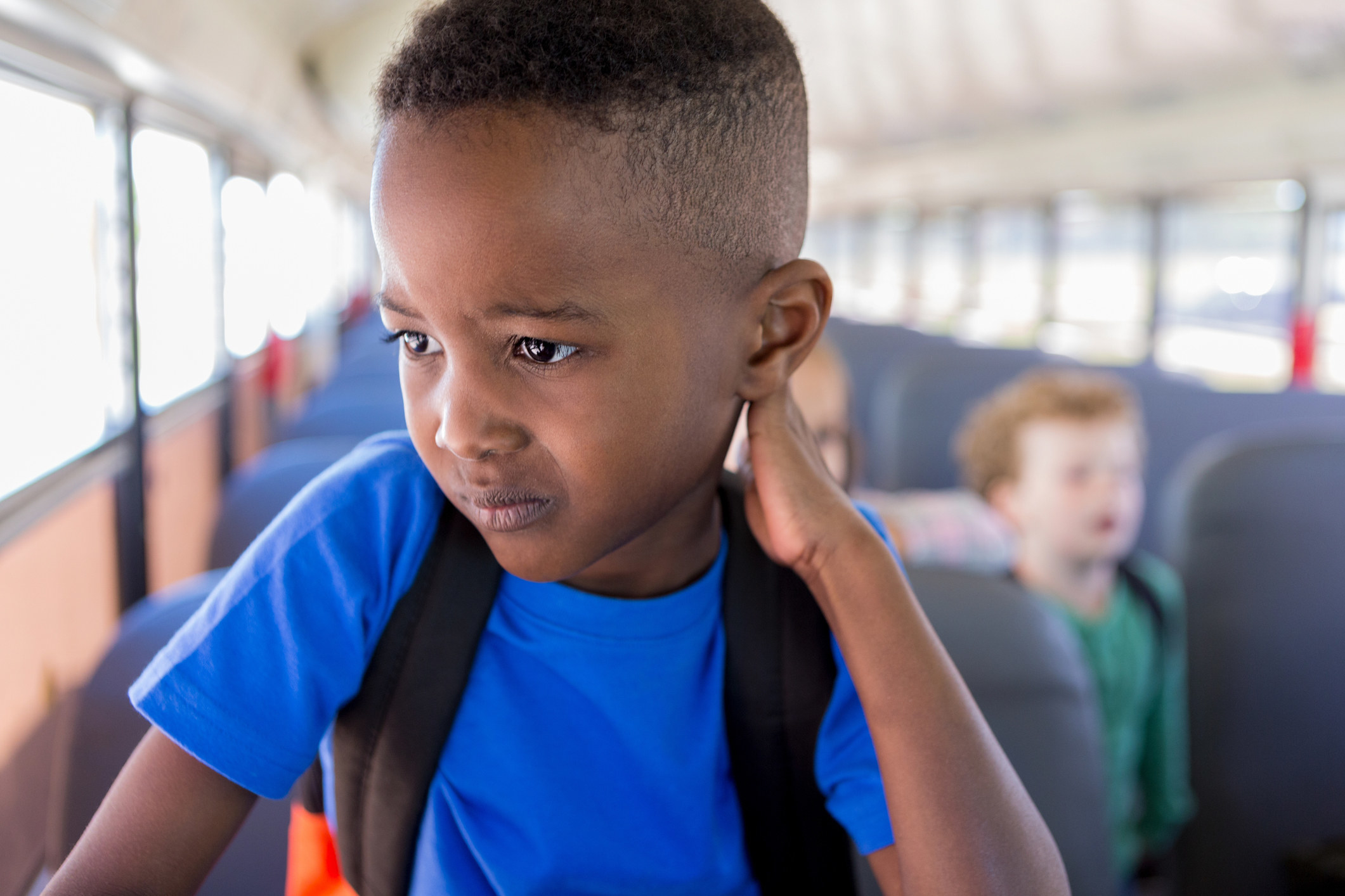 A little boy looking stressed and sad on a school bus