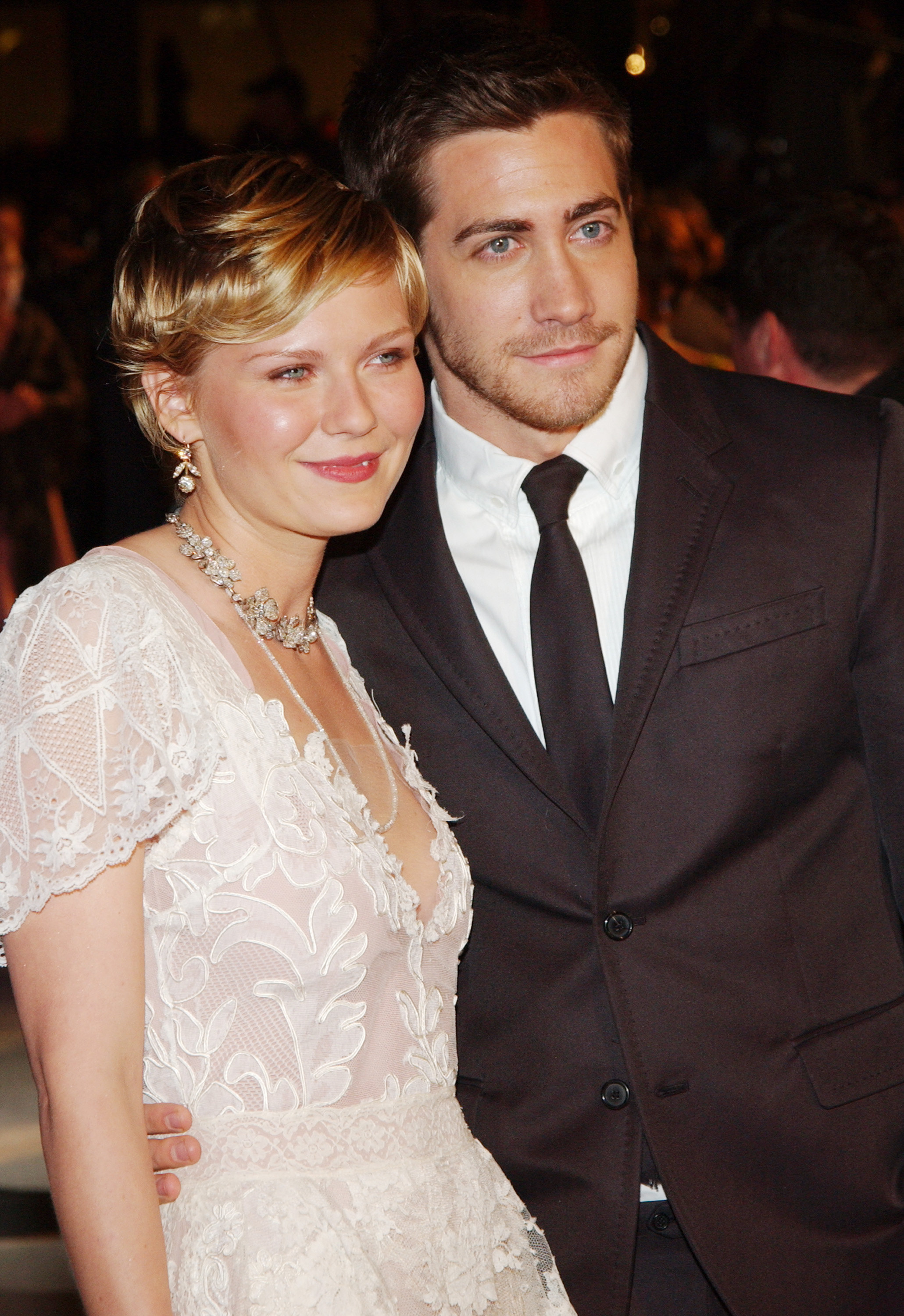 Kristen Dunst in a lace dress and Jake Gyllenhaal with their arms around each other at the 2004 Vanity Fair Oscar Party