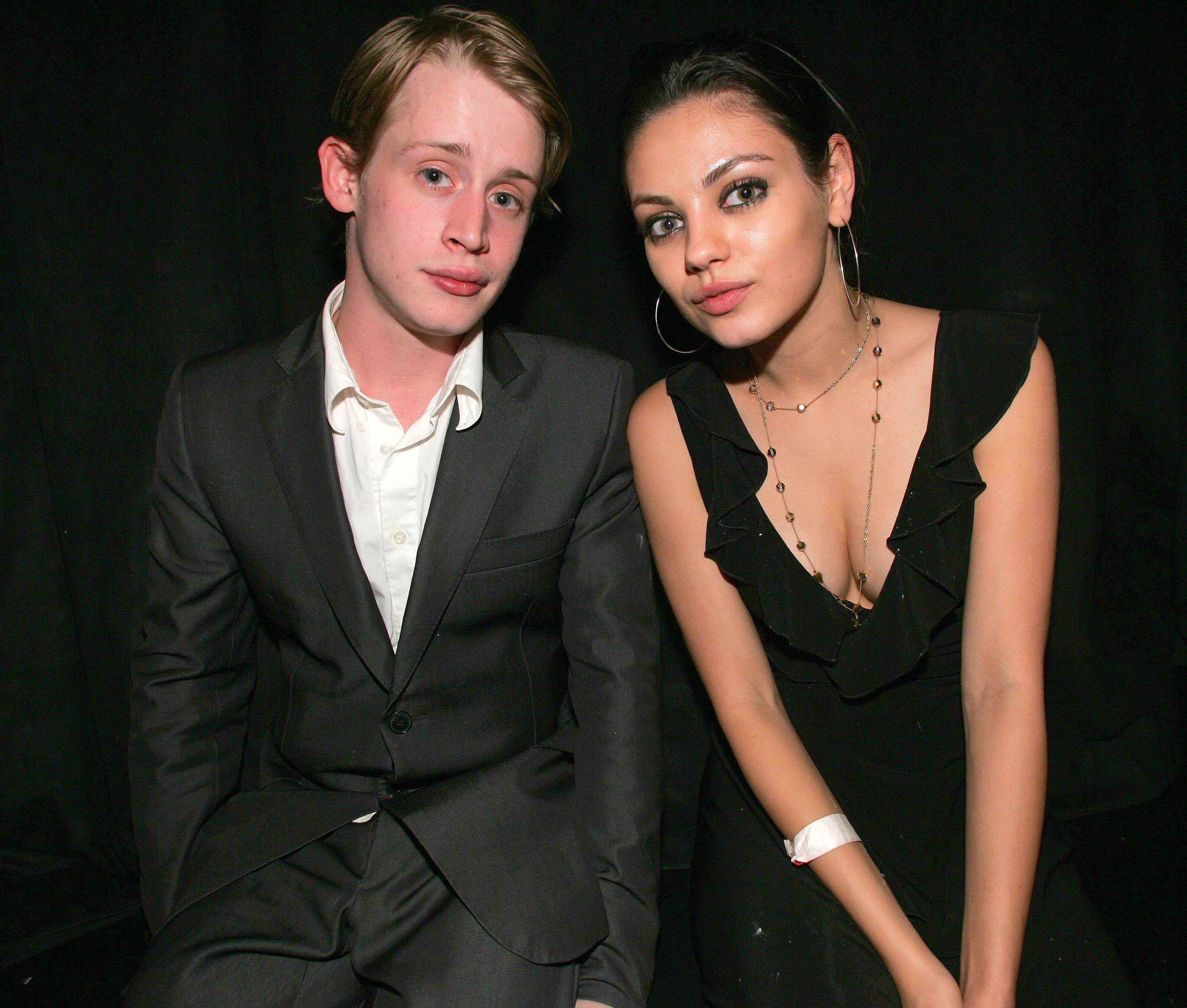 Macaulay Culkin and Mila Kunis sitting next to each at an event