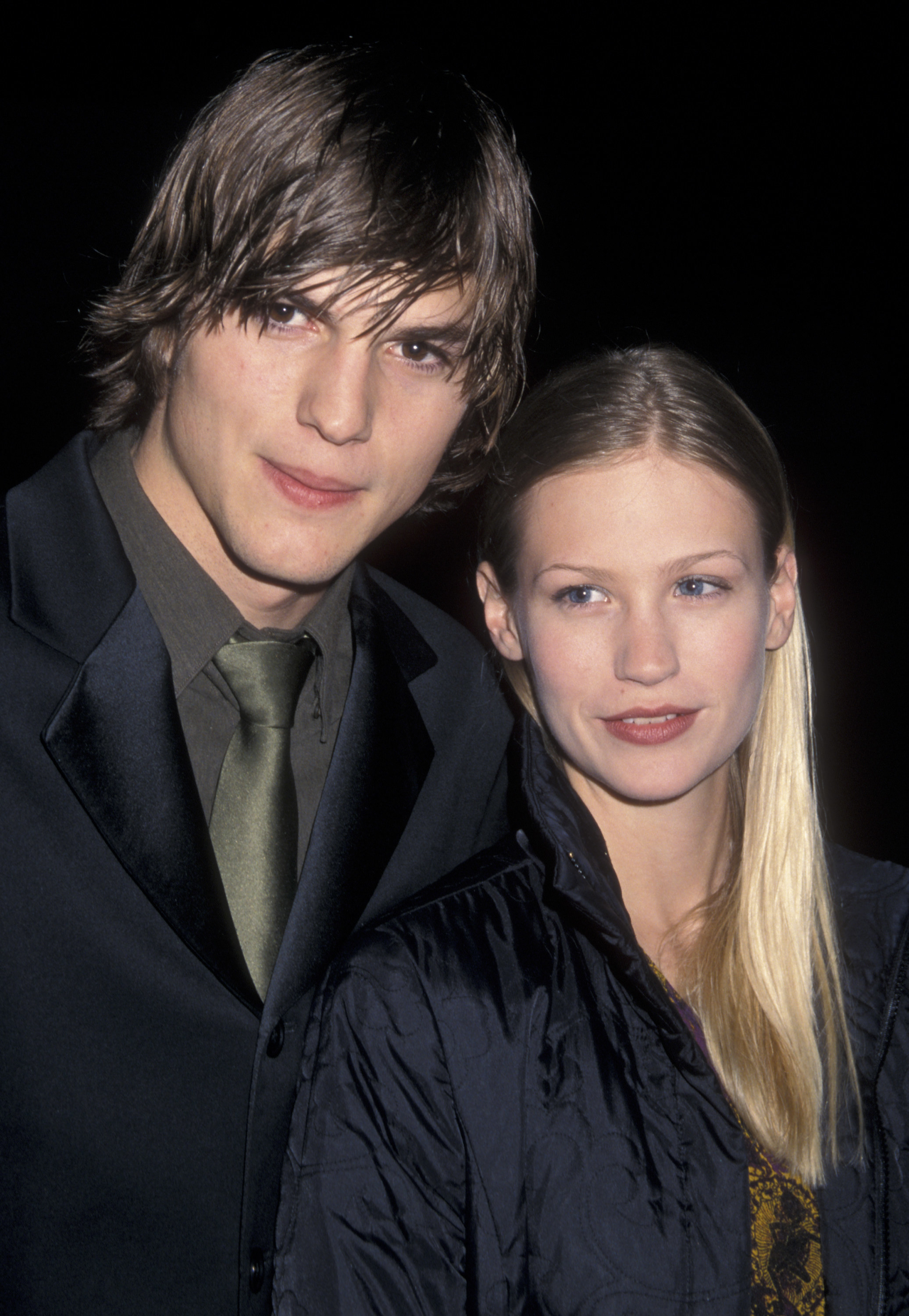 Ashton Kutcher with a shaggy haircut and dark suit, and tie standing next to January Jones who&#x27;s wearing a dark jacket at the premiere of Reindeer Games