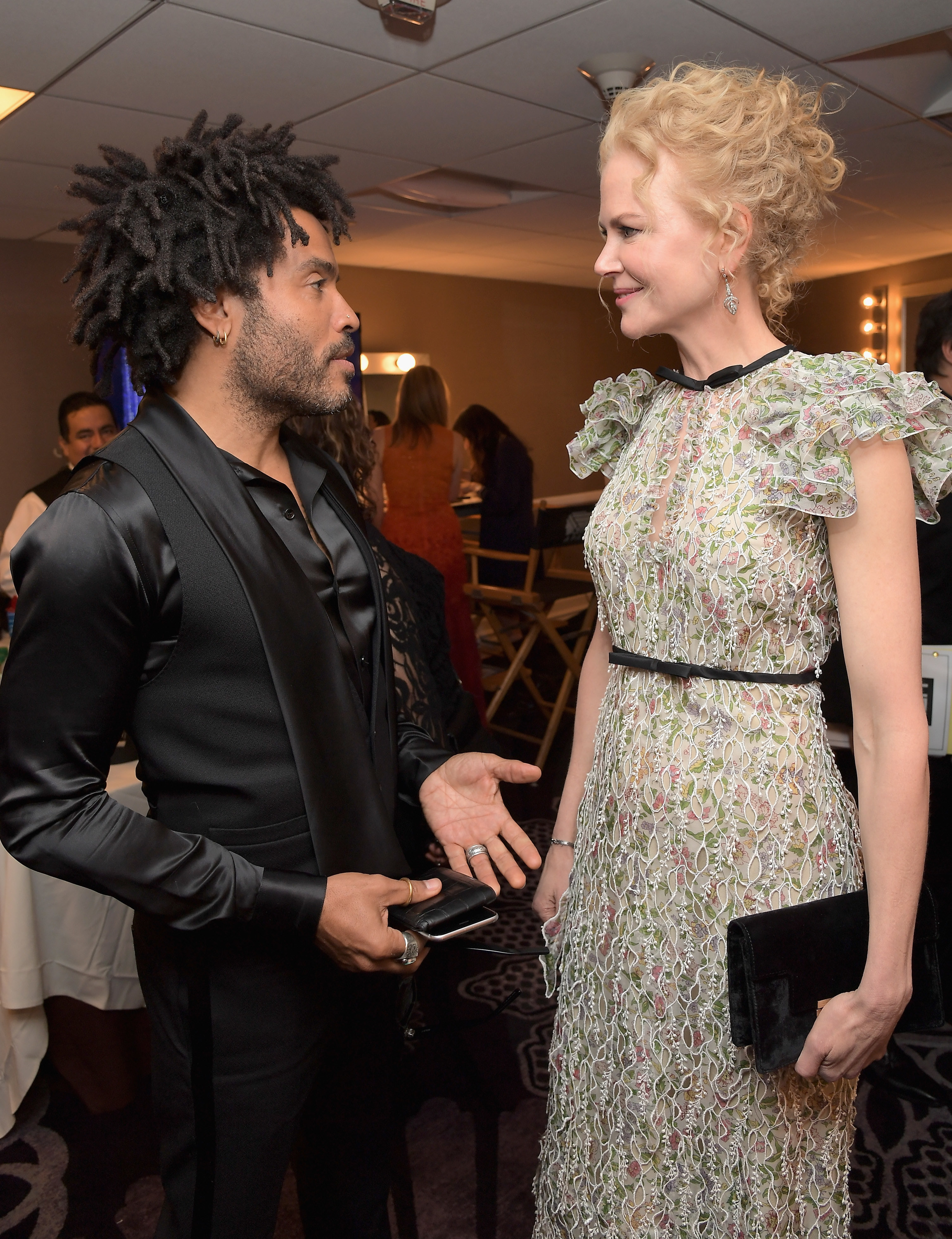 Lenny Kravitz in a black suit and Nicole Kidman in a floral gown talking together