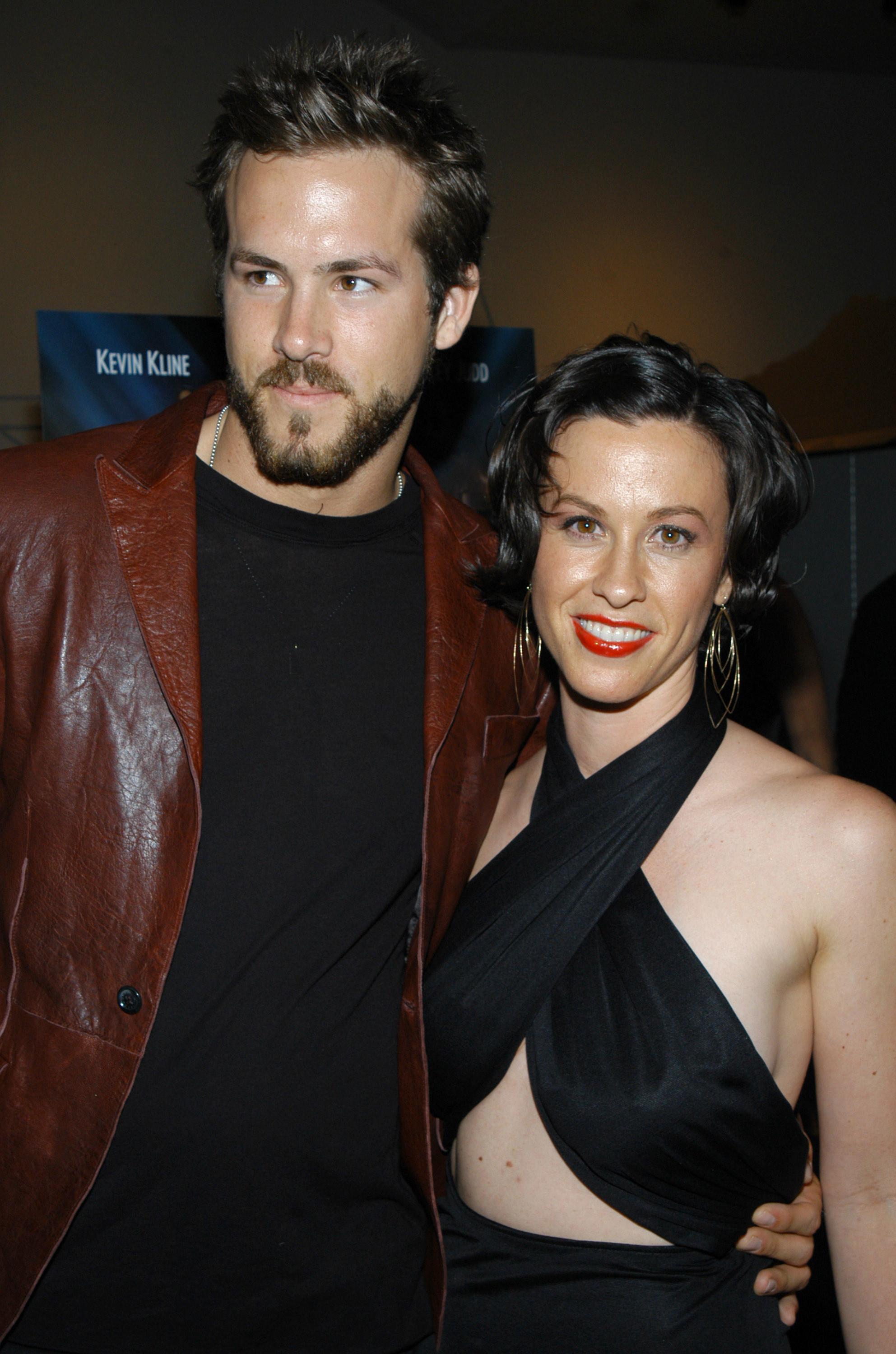 Ryan Reynolds wearing a leather jacket as he stands with his arm around Alanis Morissette, who&#x27;s wearing a halter top at a premiere