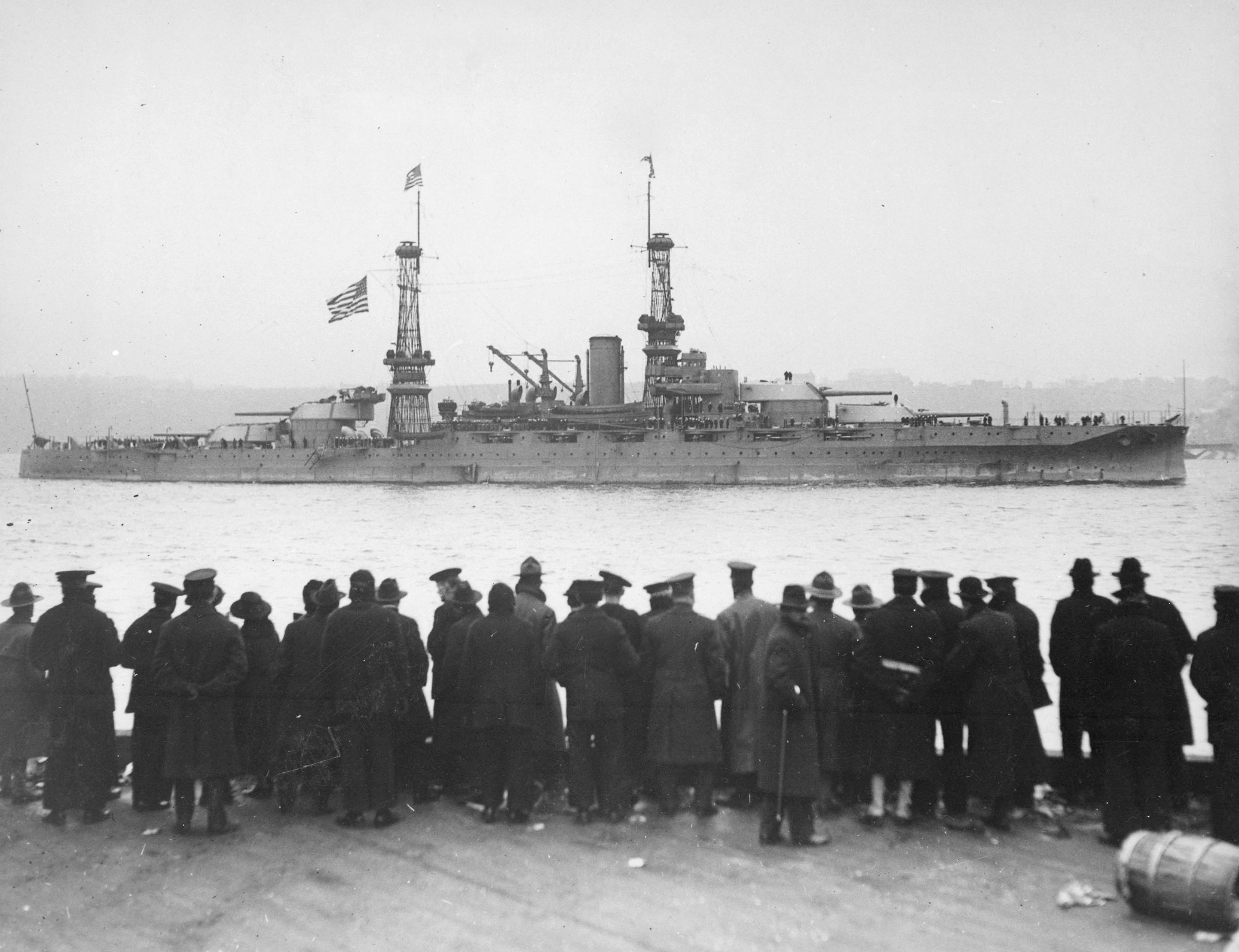 Black-and-white photo of people standing at a dock and looking at a large ship