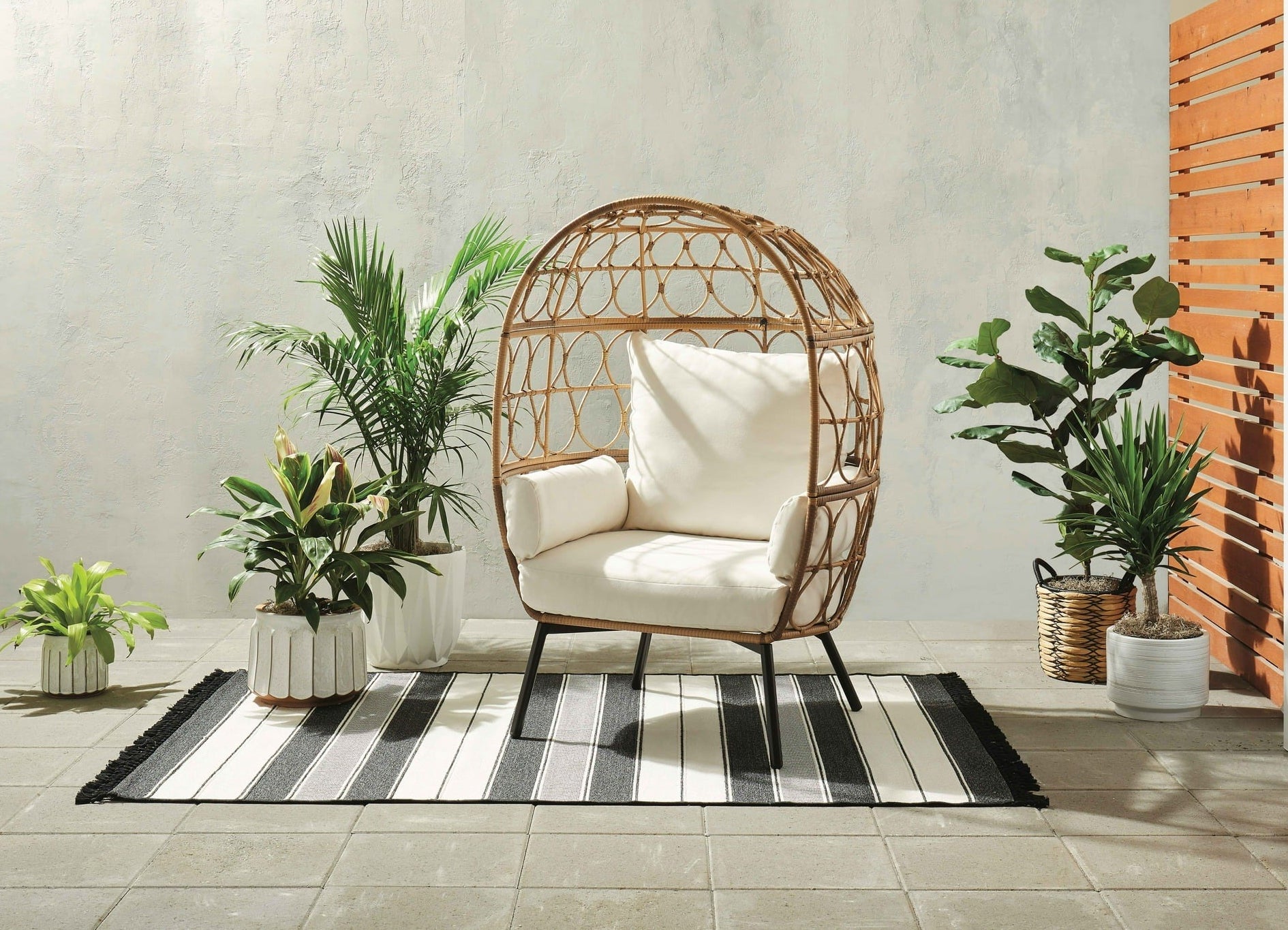 the wicker egg chair with multiple cushions on a patio