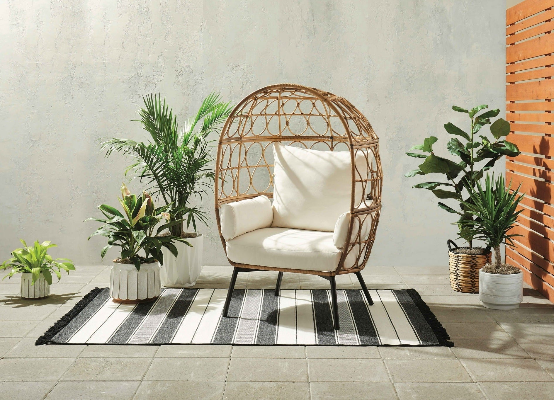 the wicker egg chair with multiple cushions on a patio