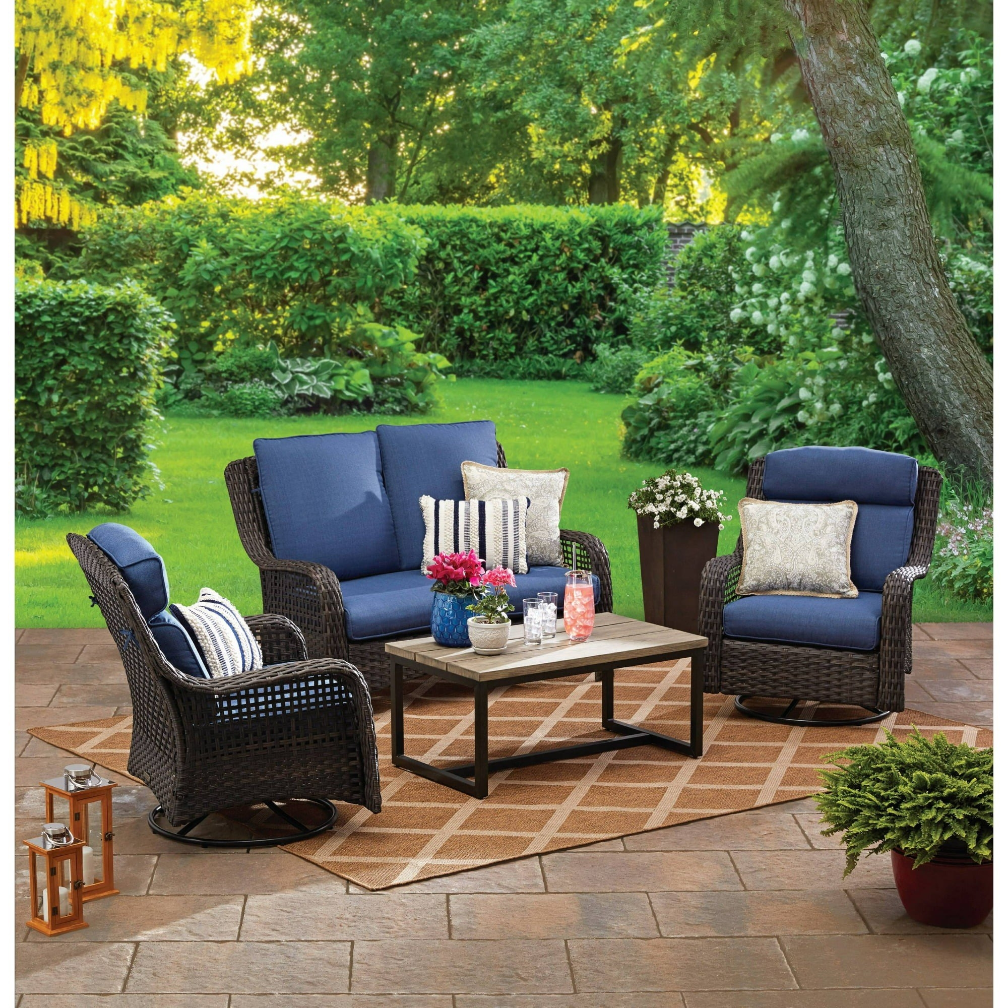 the four-piece furniture set with a loveseat, two swivel chairs, and a coffee table in a backyard