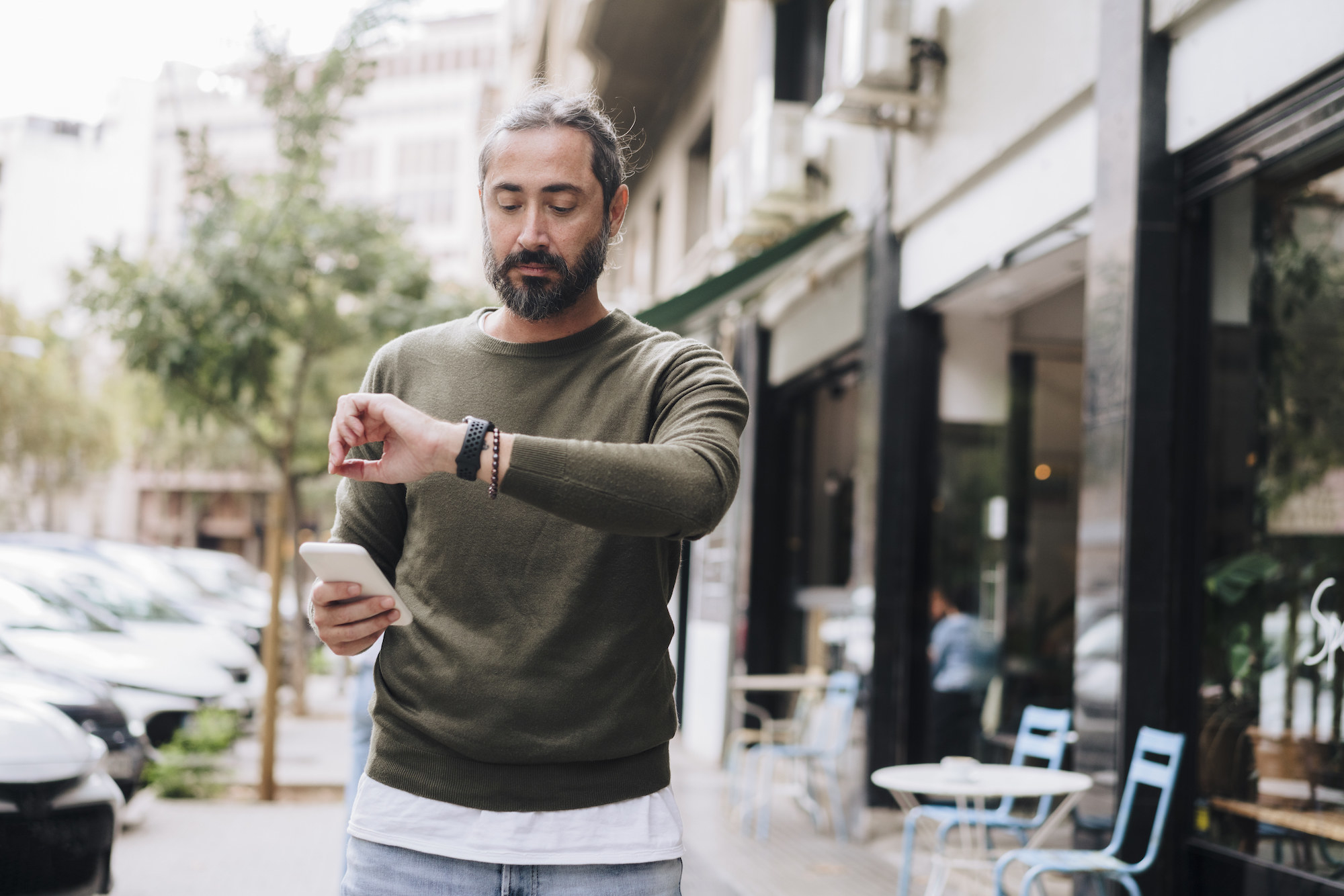 A man holding his phone while checking his watch