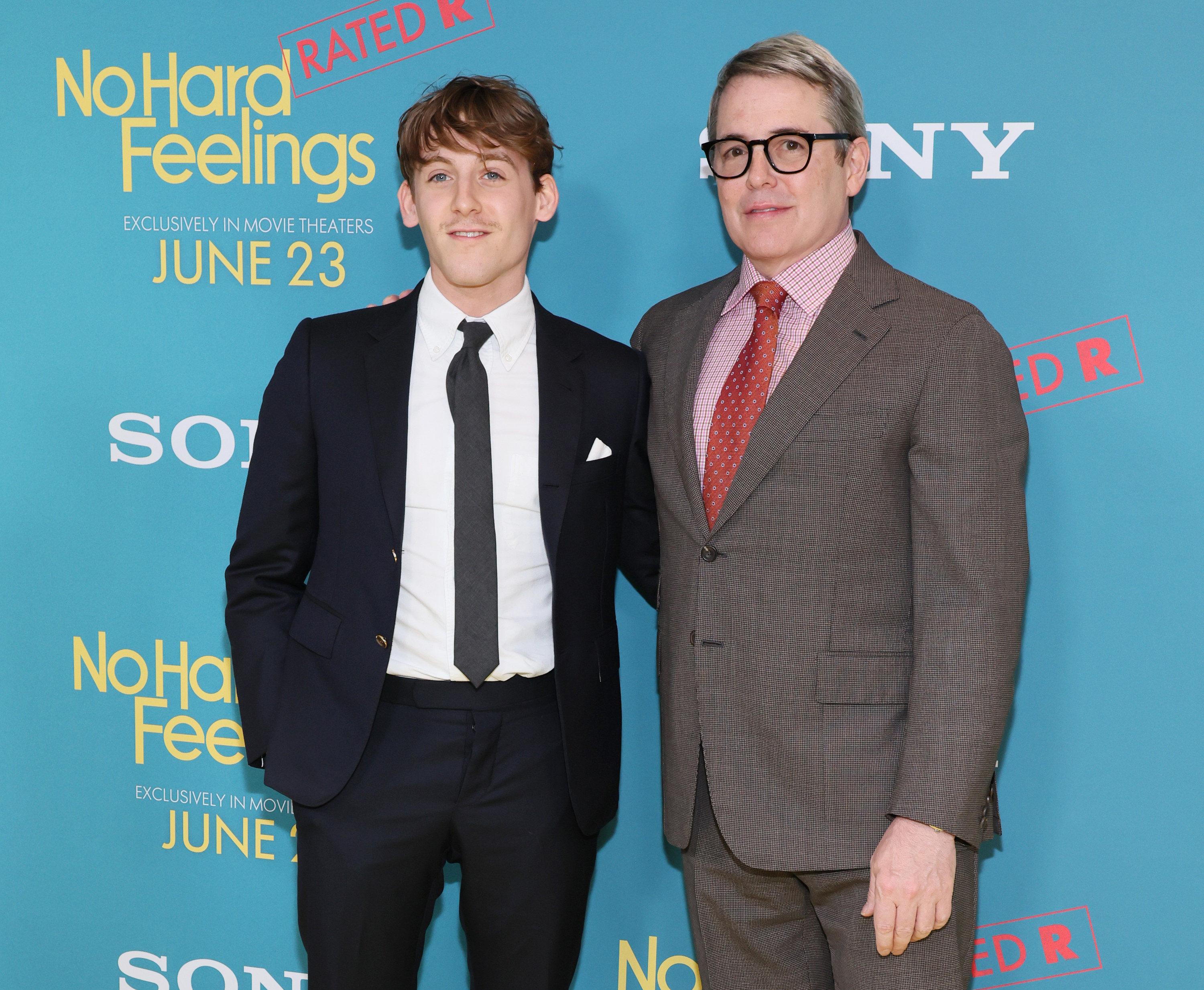 Matthew with his son, both wearing a suit and tie, at a media event