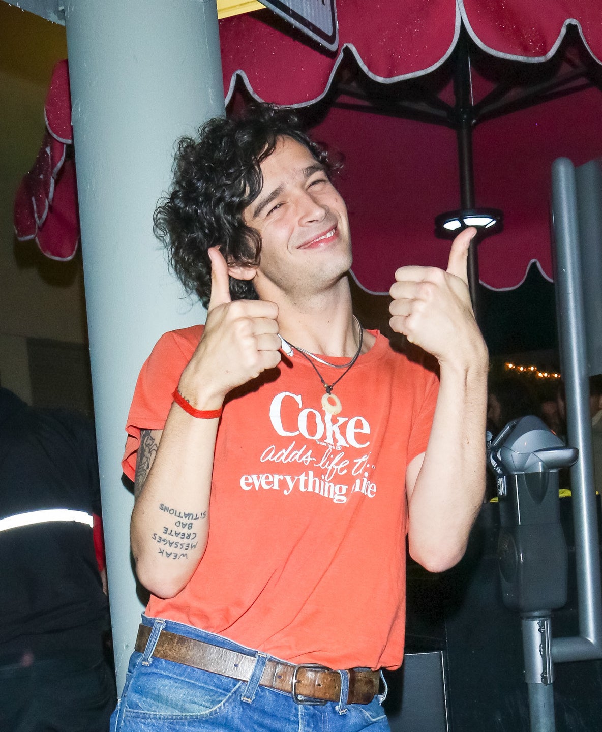 Close-up of Matty smiling, wearing a &quot;Coke adds life to everything nice&quot; T-shirt, and giving two thumbs-up