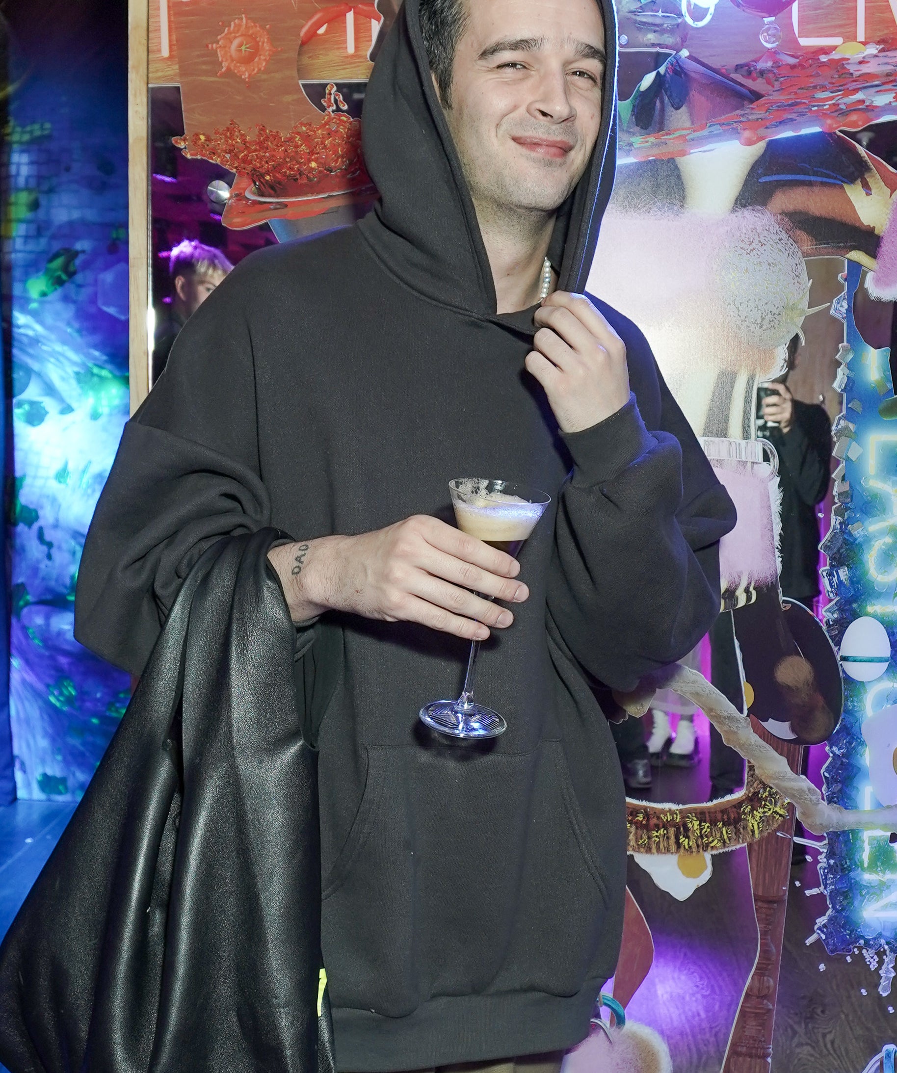 Close-up of Matty in a hoodie and holding a drink