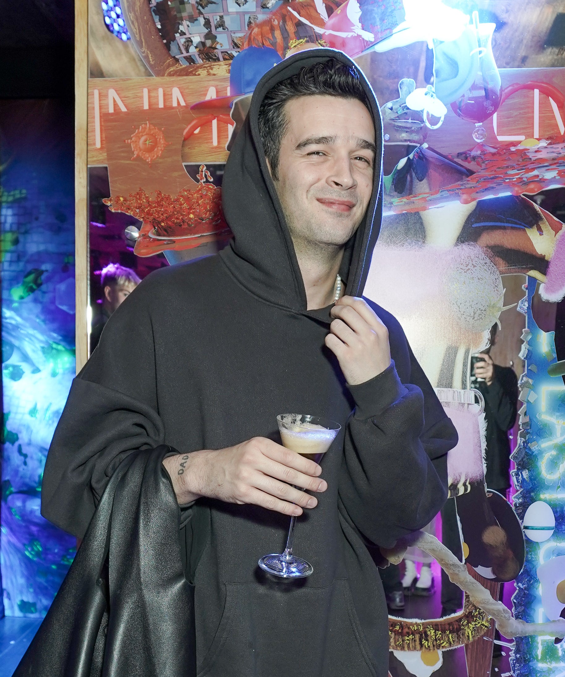 Close-up of Matty in a hoodie and holding a drink