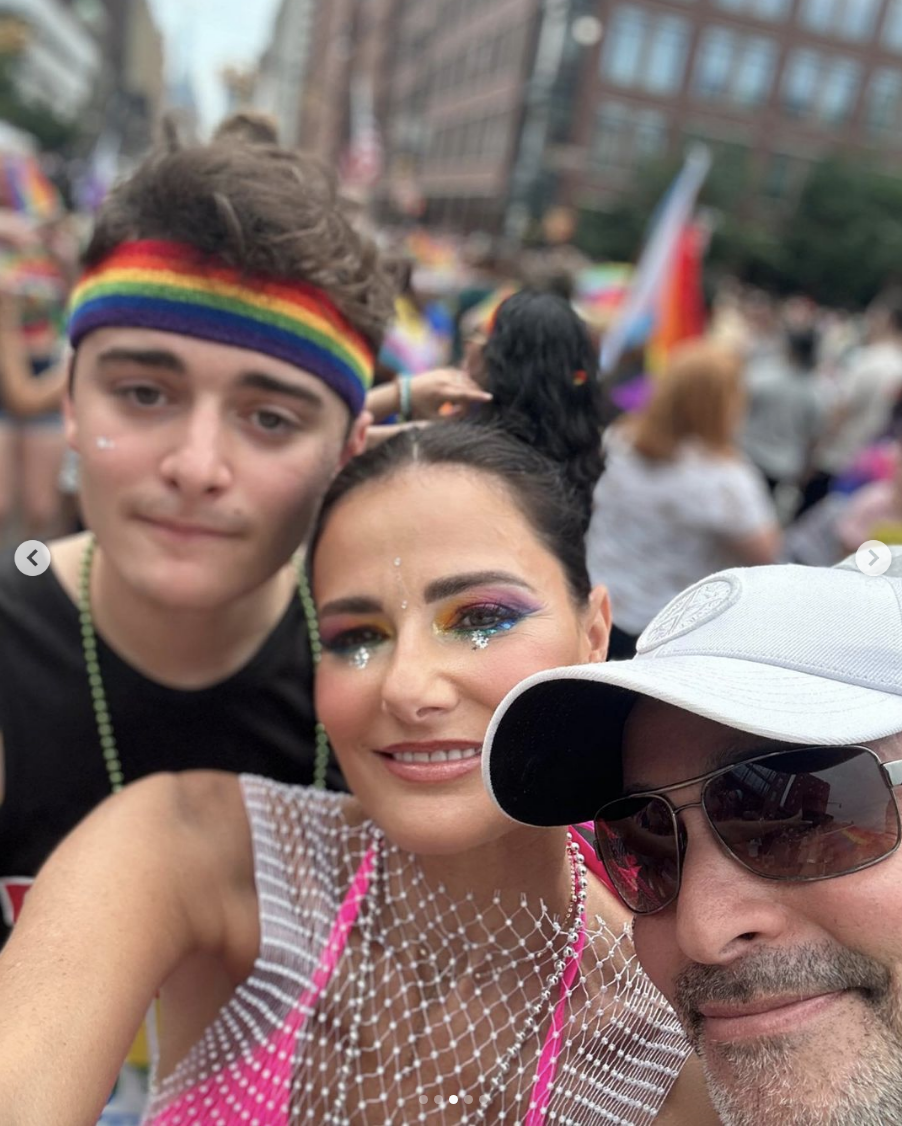 Noah, wearing a pride flag headband, and his parents at Pride
