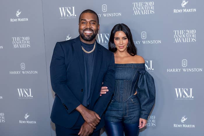 Ye and Kim smiling arm-in-arm at a media event