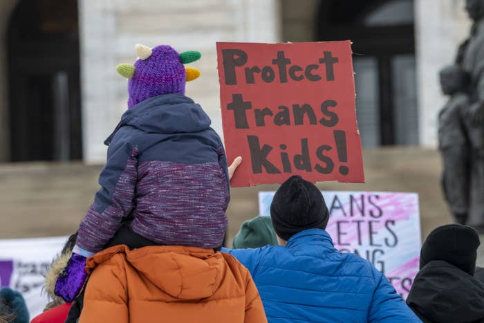 Someone holding a sign that says, &quot;Protect trans kids&quot;