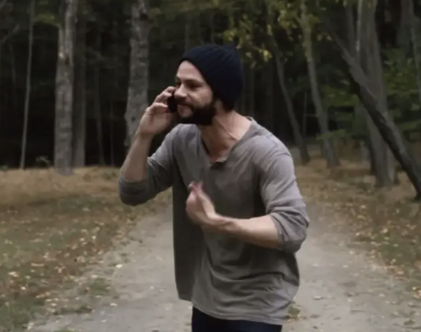Dylan speaking on the phone while walking on a trail in the woods
