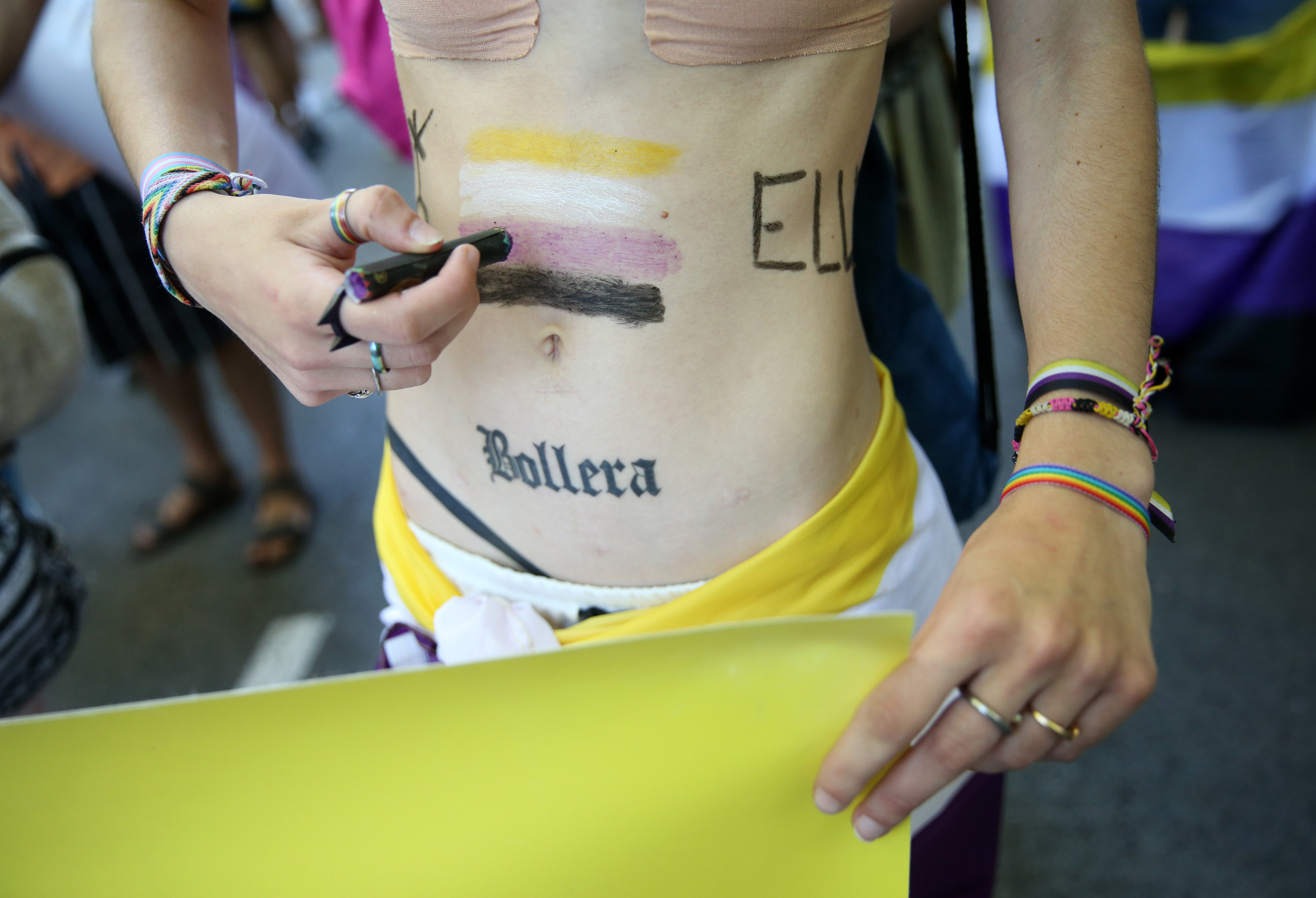 A person painting the nonbinary flag on their stomach