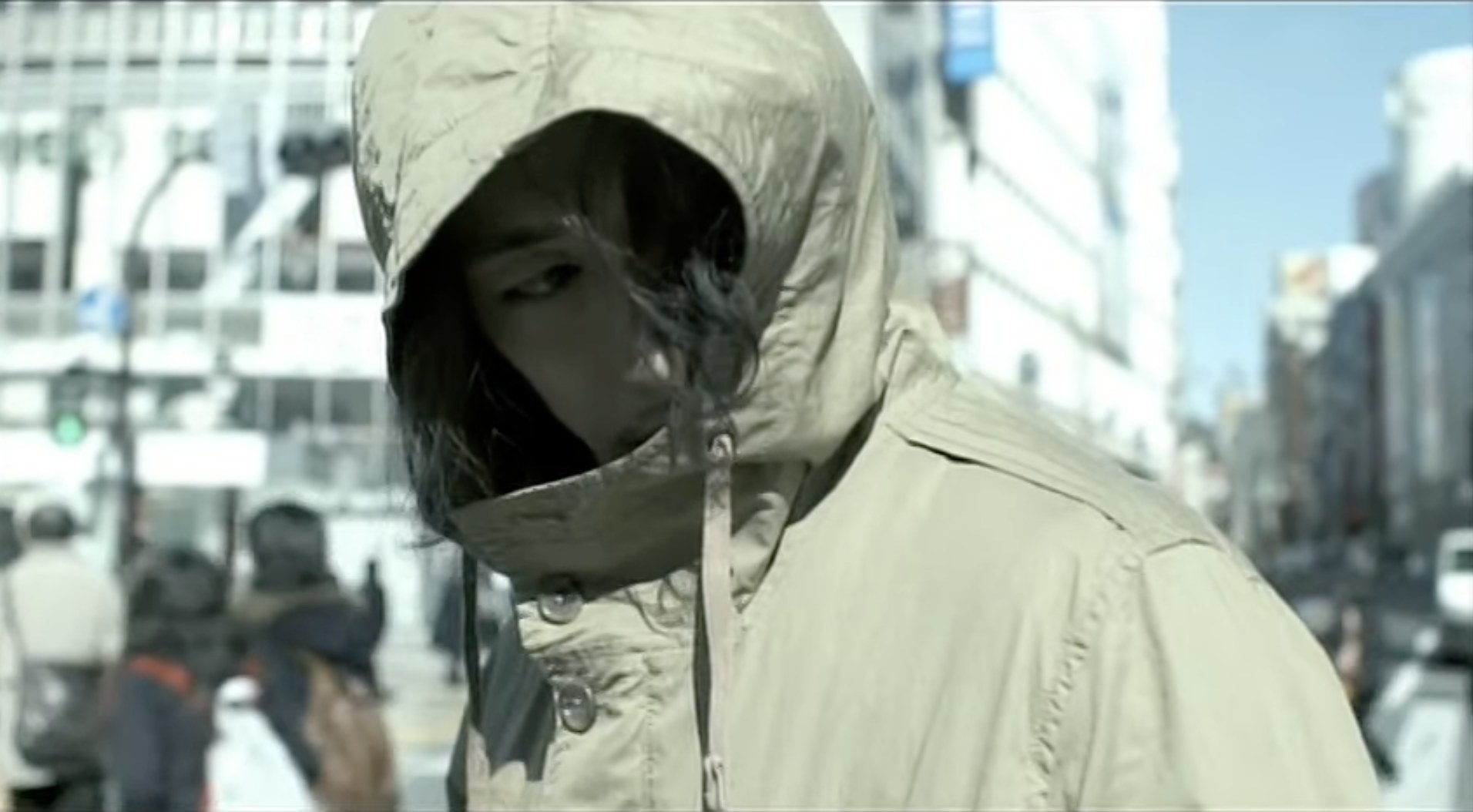 Screenshot from &quot;I am Ichihashi: Journal of a Murderer,&quot; with actor Dean Fujioka playing Ichihashi; he&#x27;s walking in a crowded street hiding his face under a brown hoodie