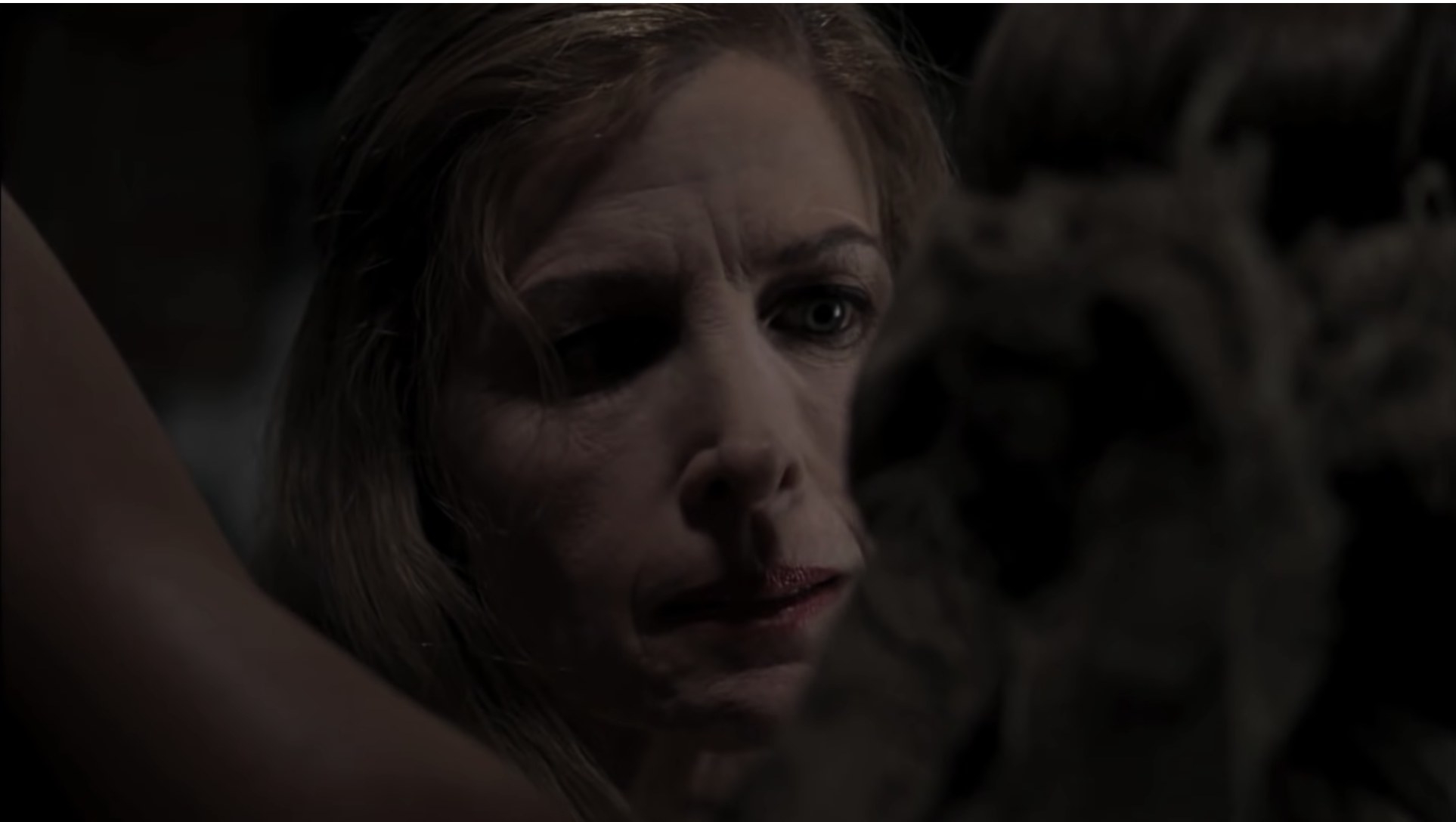 Still from the movie &quot;The Girl Next Door&quot; with actor Blanche Baker in the dark, looking menacingly at a woman who has been tied up