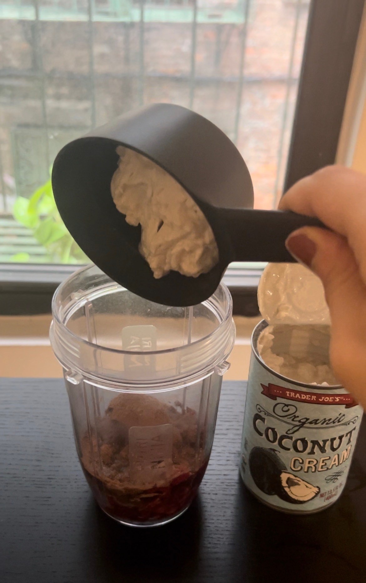 Coconut cream is poured into a blender