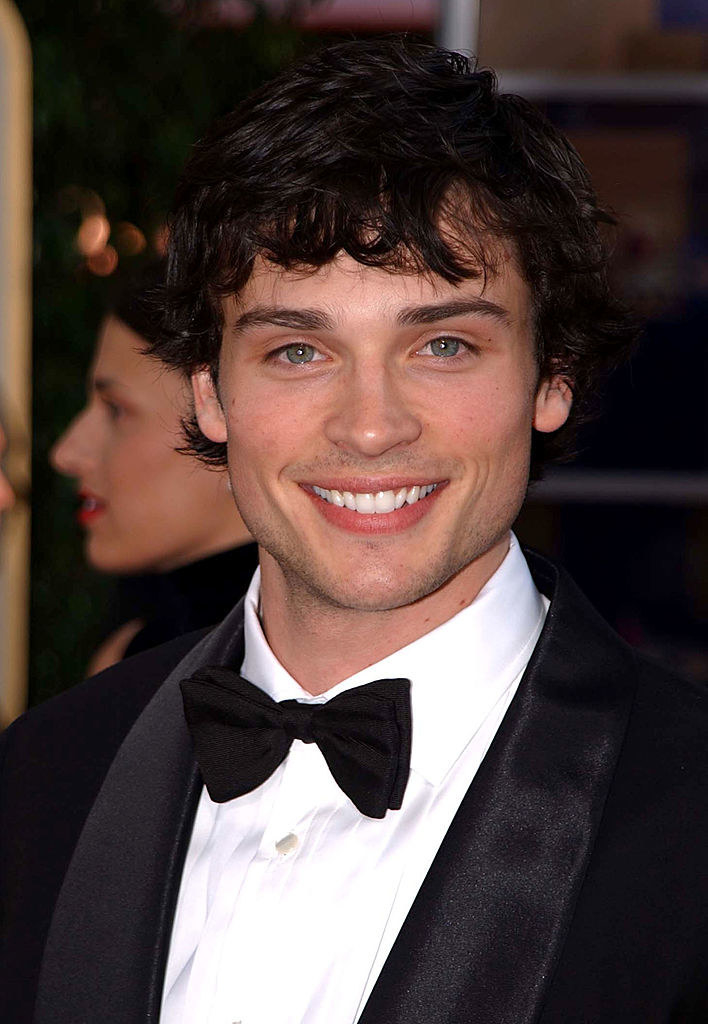 long messy smile and light stubble wearing a bowtie and suit