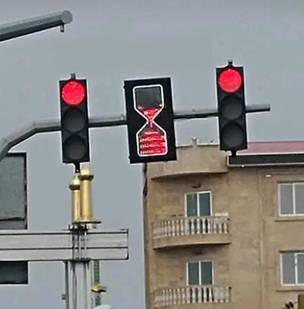 traffic lights with a light in the middle that is shaped like an hour glass showing light pour down into the lower section