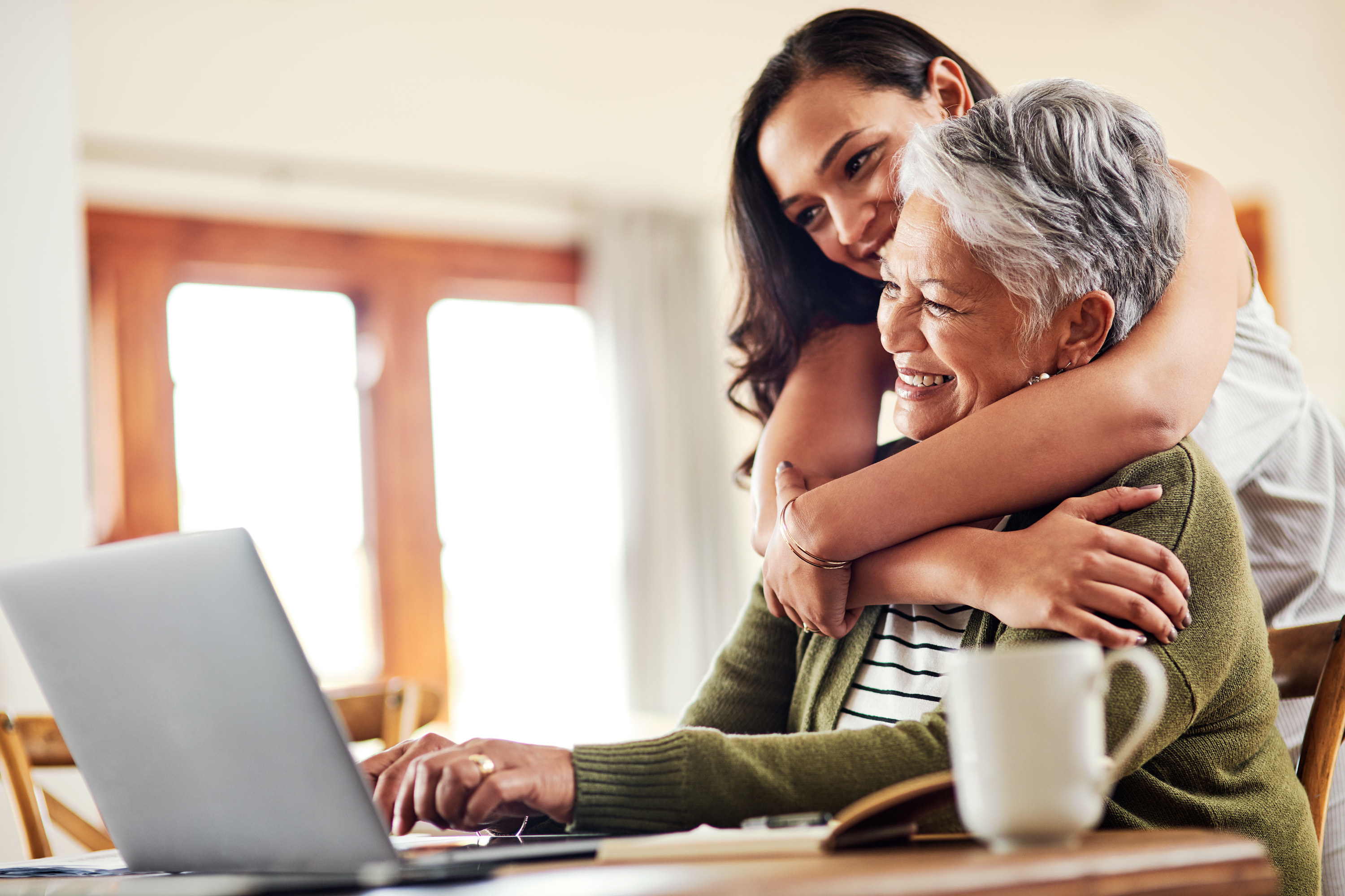 a mother and daughter hugging while using the computer