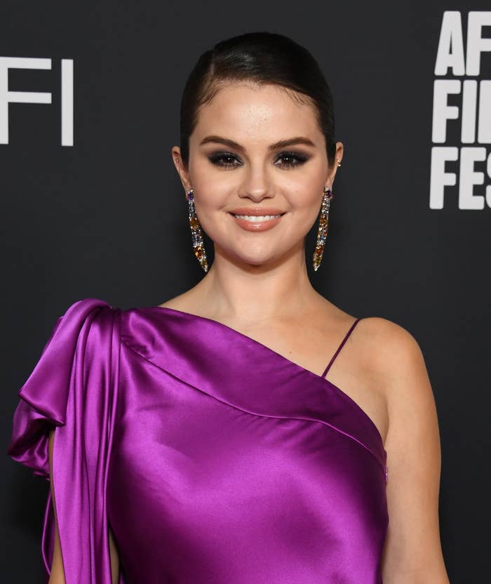 Close-up of Selena smiling and wearing a satiny, one-shoulder outfit