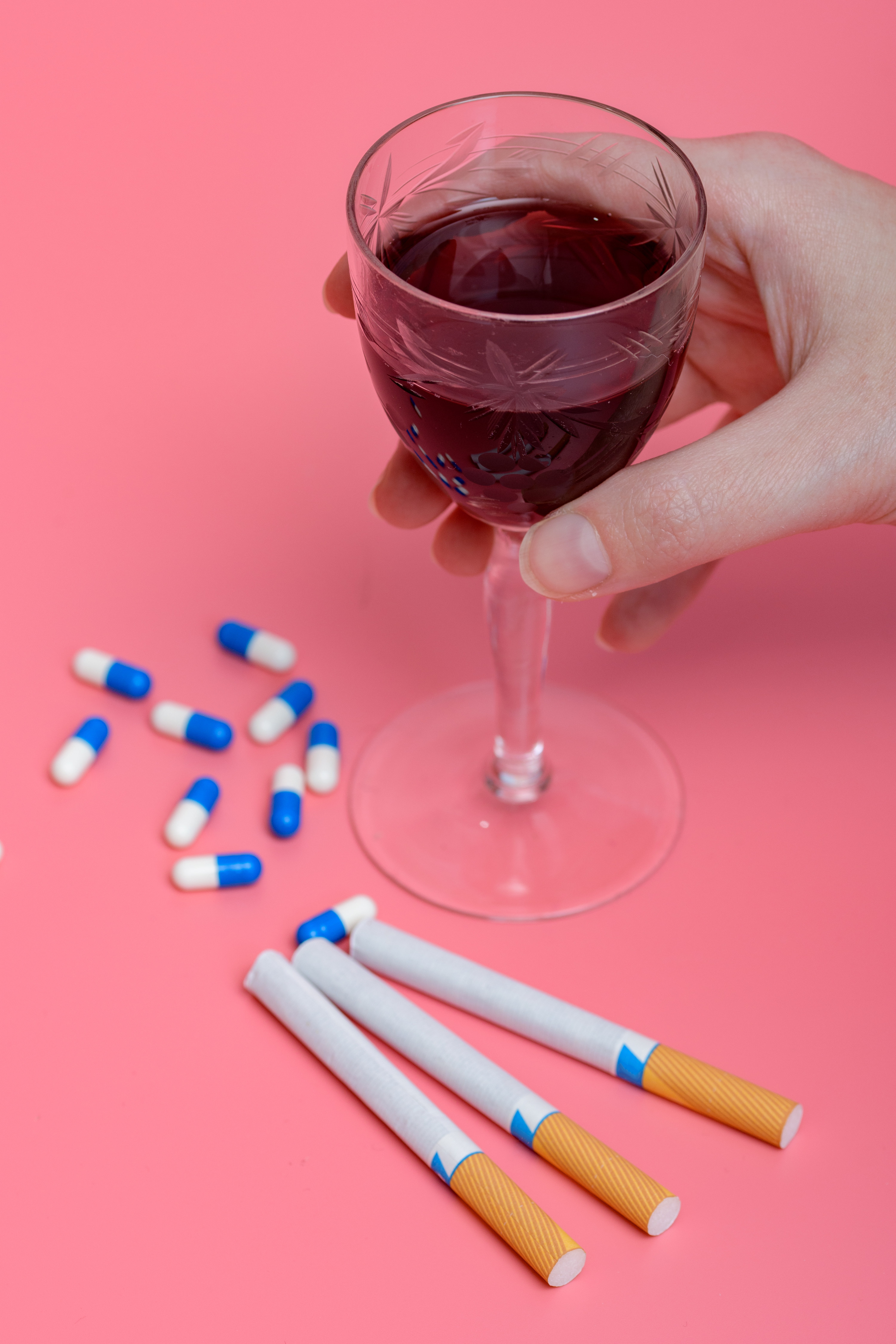 cigarettes pills and a glass of wine