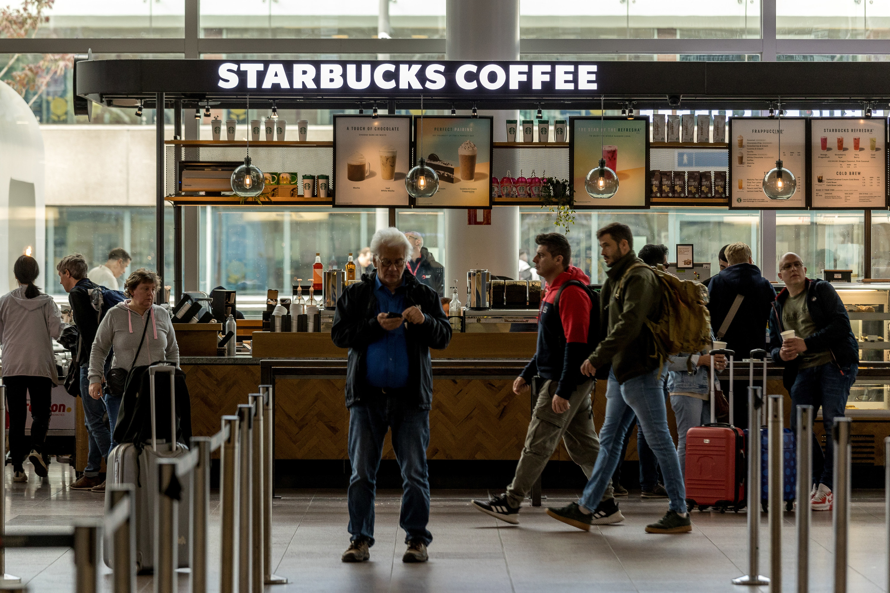 Passengers walk past a Starbucks coffee shop inside the departure terminal of the Belgian capital&#x27;s airport