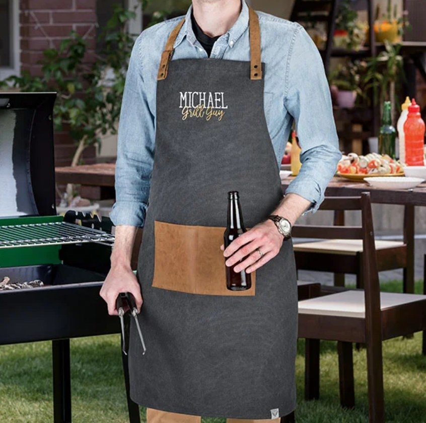 a model wearing the apron with &quot;michael grill guy&quot; slogan