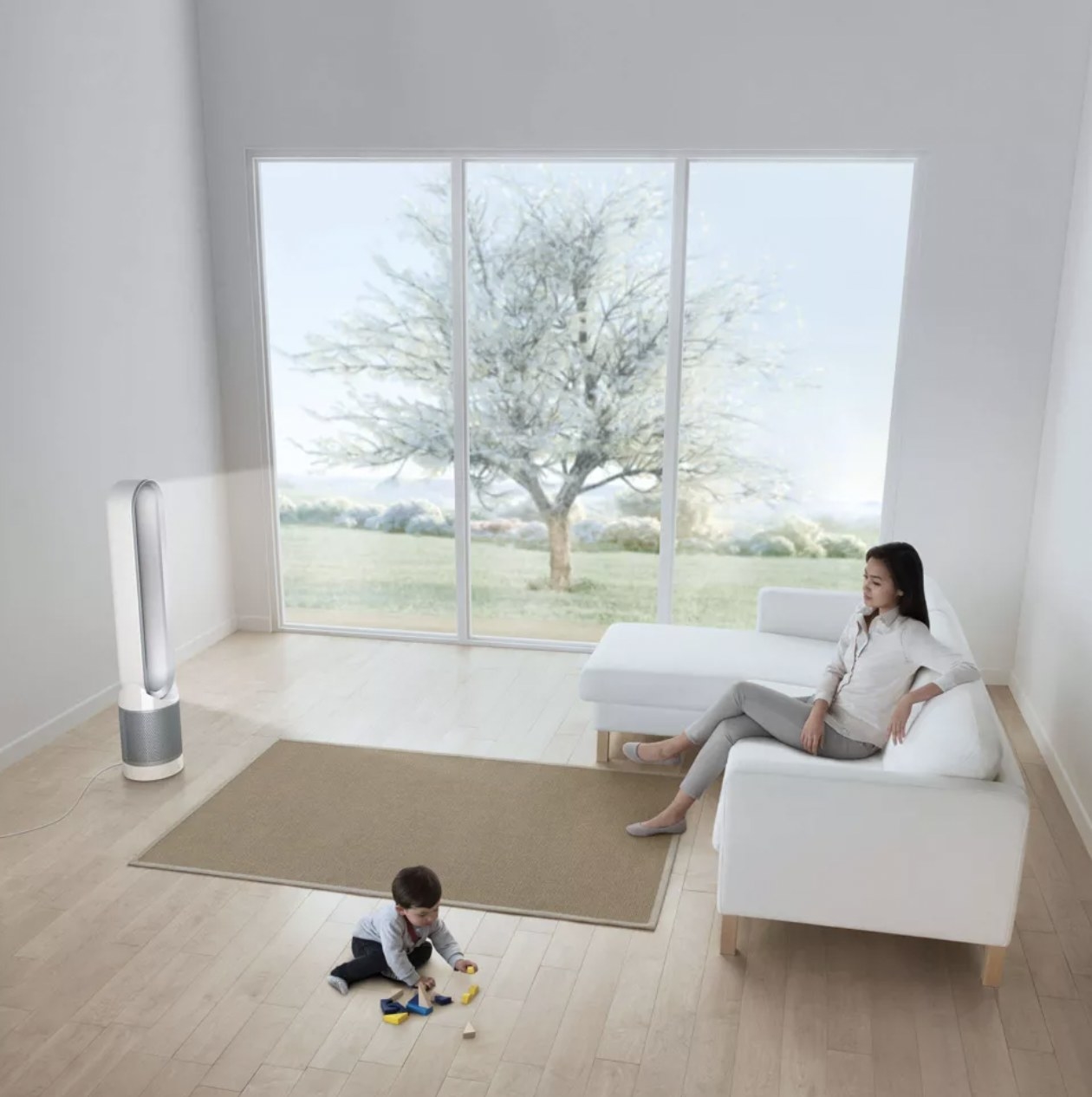 The fan tower blowing clean air at parent on couch while child plays on floor