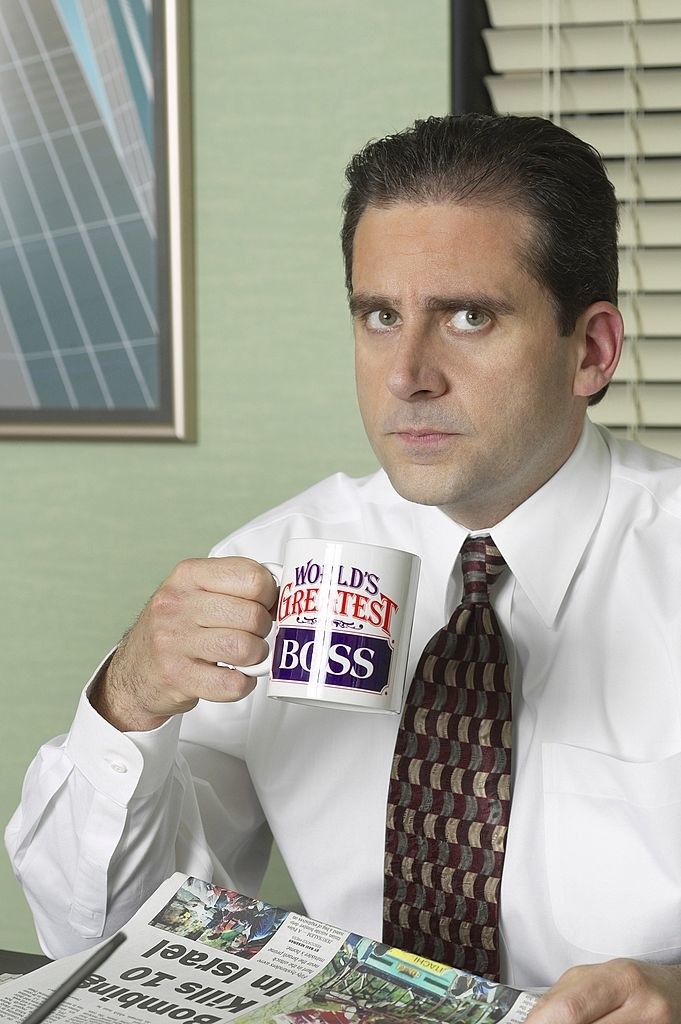 Closeup of Michael Scott reading the paper and drinking coffee