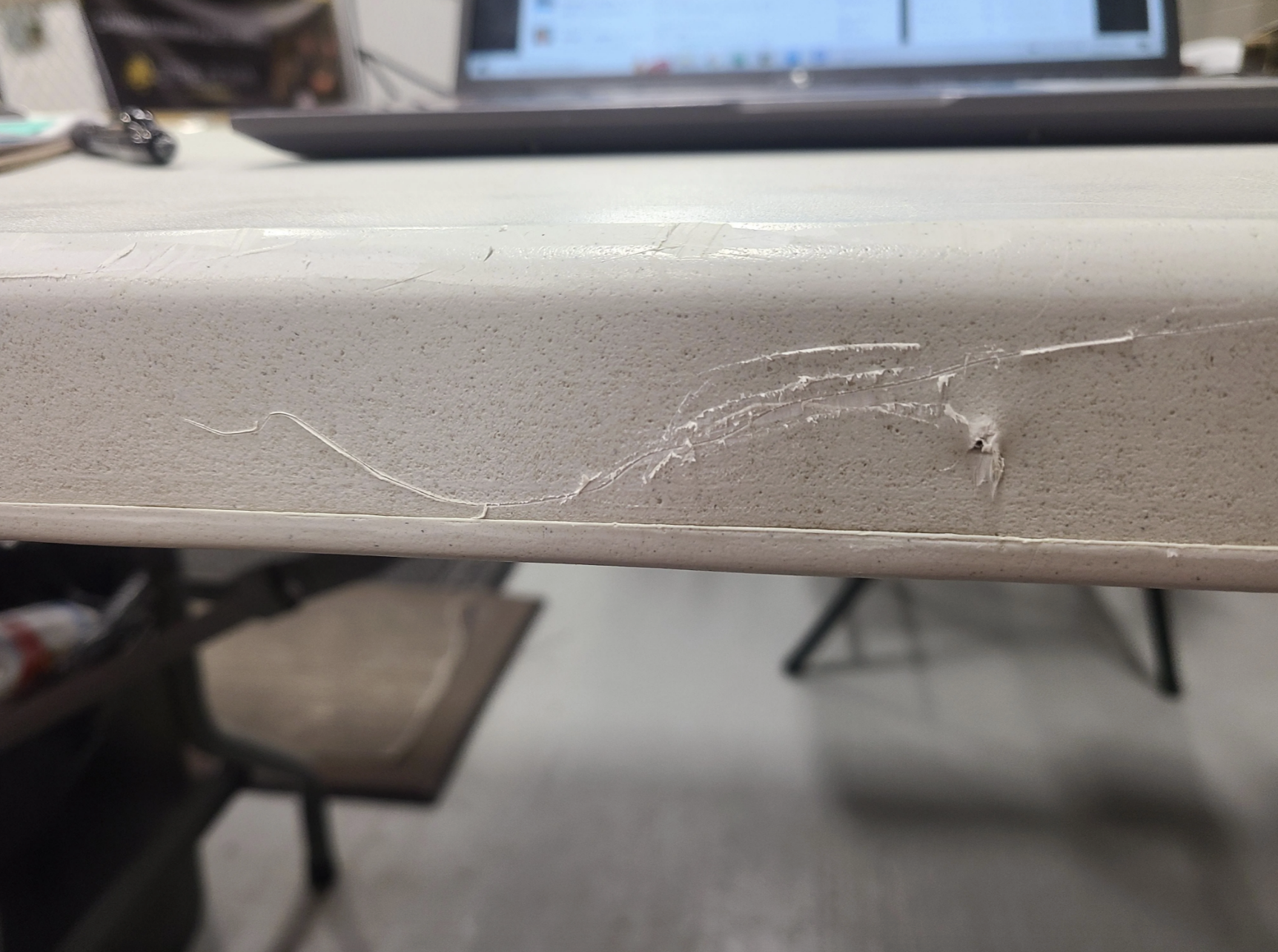 A table in what appears to be a break room has had random lines carved into it with a knife