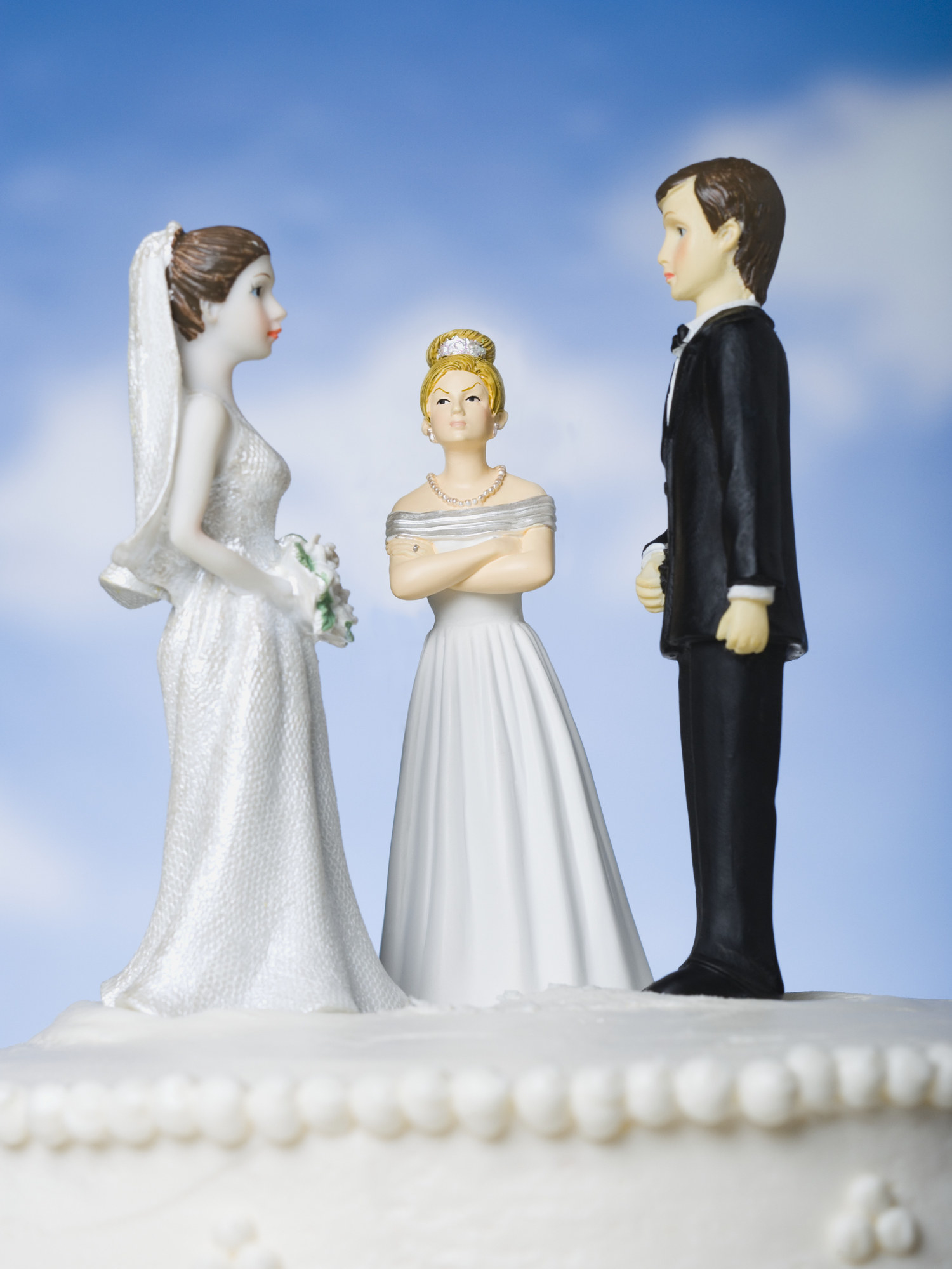 wedding cake toppers of a bride and groom and a third angry bride
