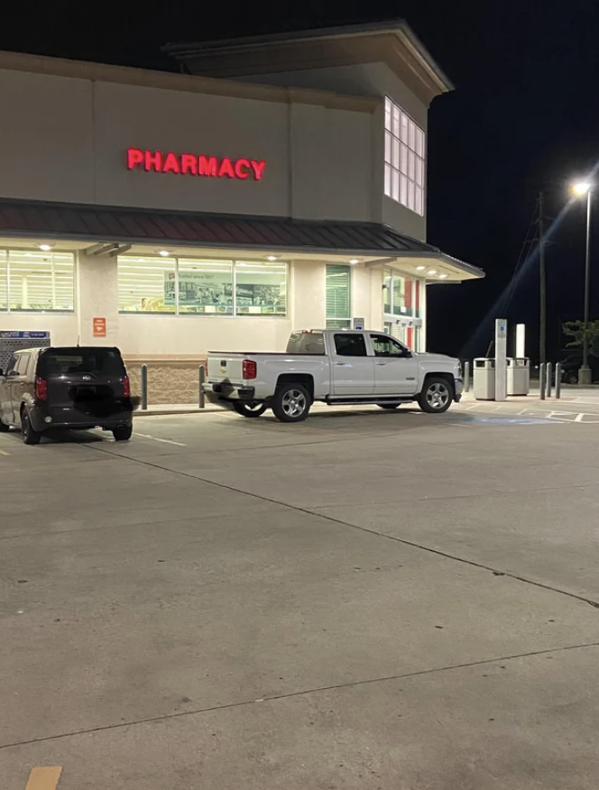 Car parked over a few different spots at a pharmacy