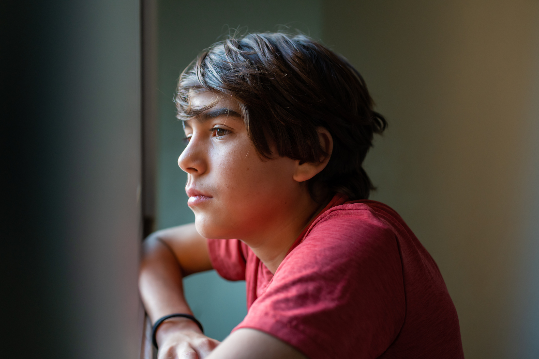 A young boy staring out a window
