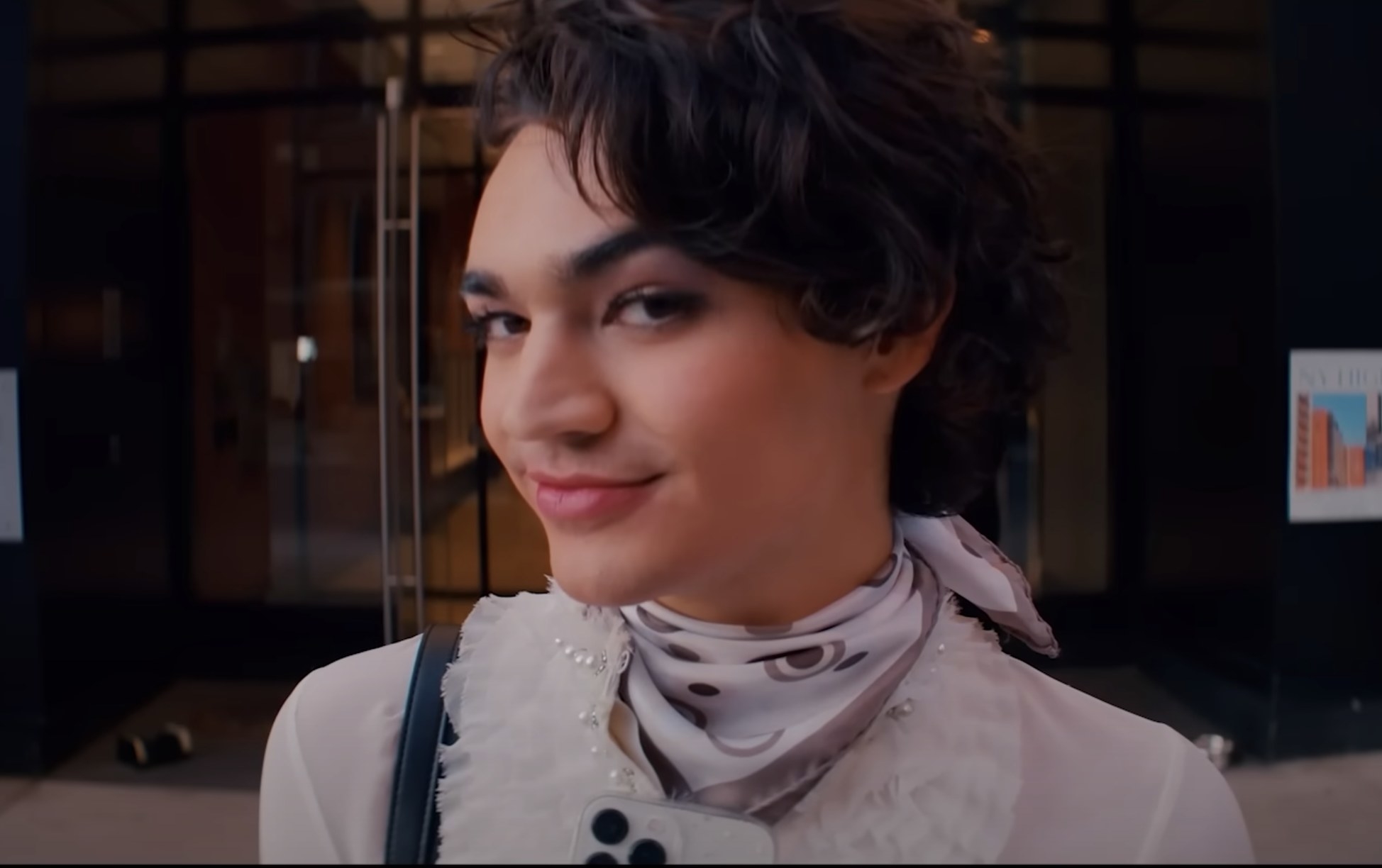 A closeup of Miss Benny in the show wearing makeup and a scarf around her neck