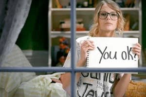 Taylor holding up a sign that says you "you ok?"