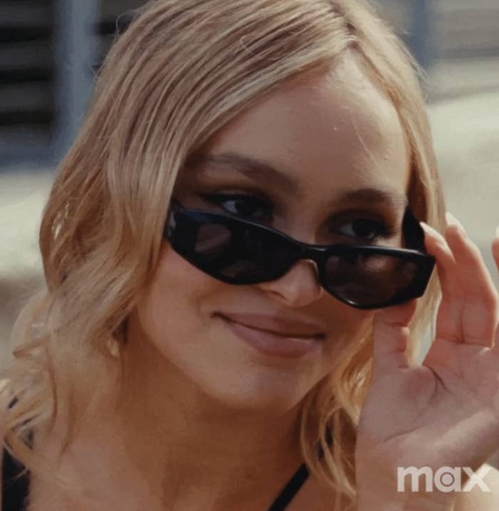 Lily-Rose Depp as Jocelyn from &quot;The Idol&quot; looking over her sunglasses as she smirks