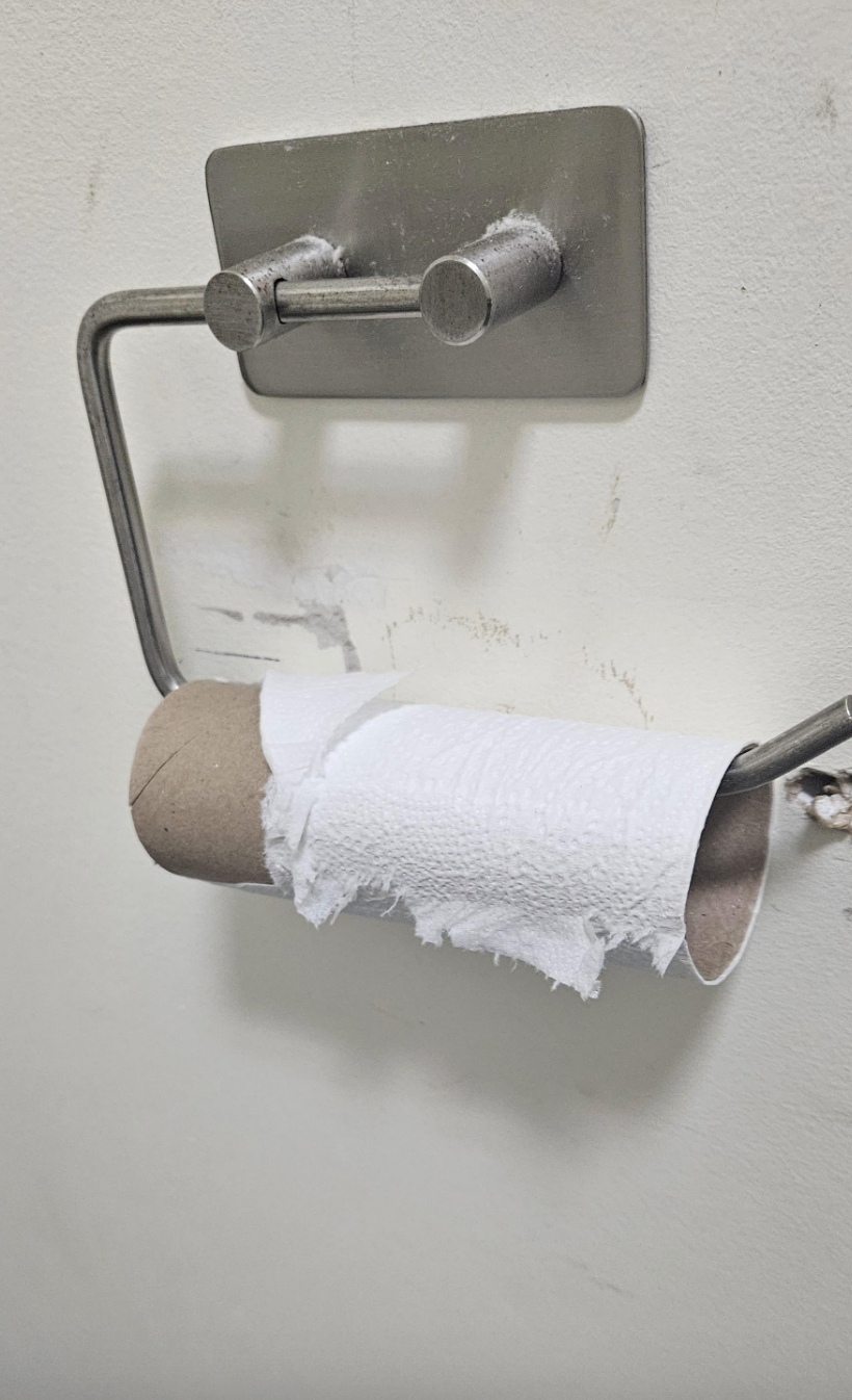 The roll of toilet paper on the holder is completely empty and has not been replaced