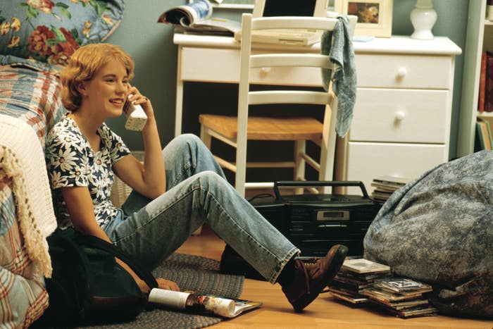 A young woman on the phone while sitting on the floor of her bedroom
