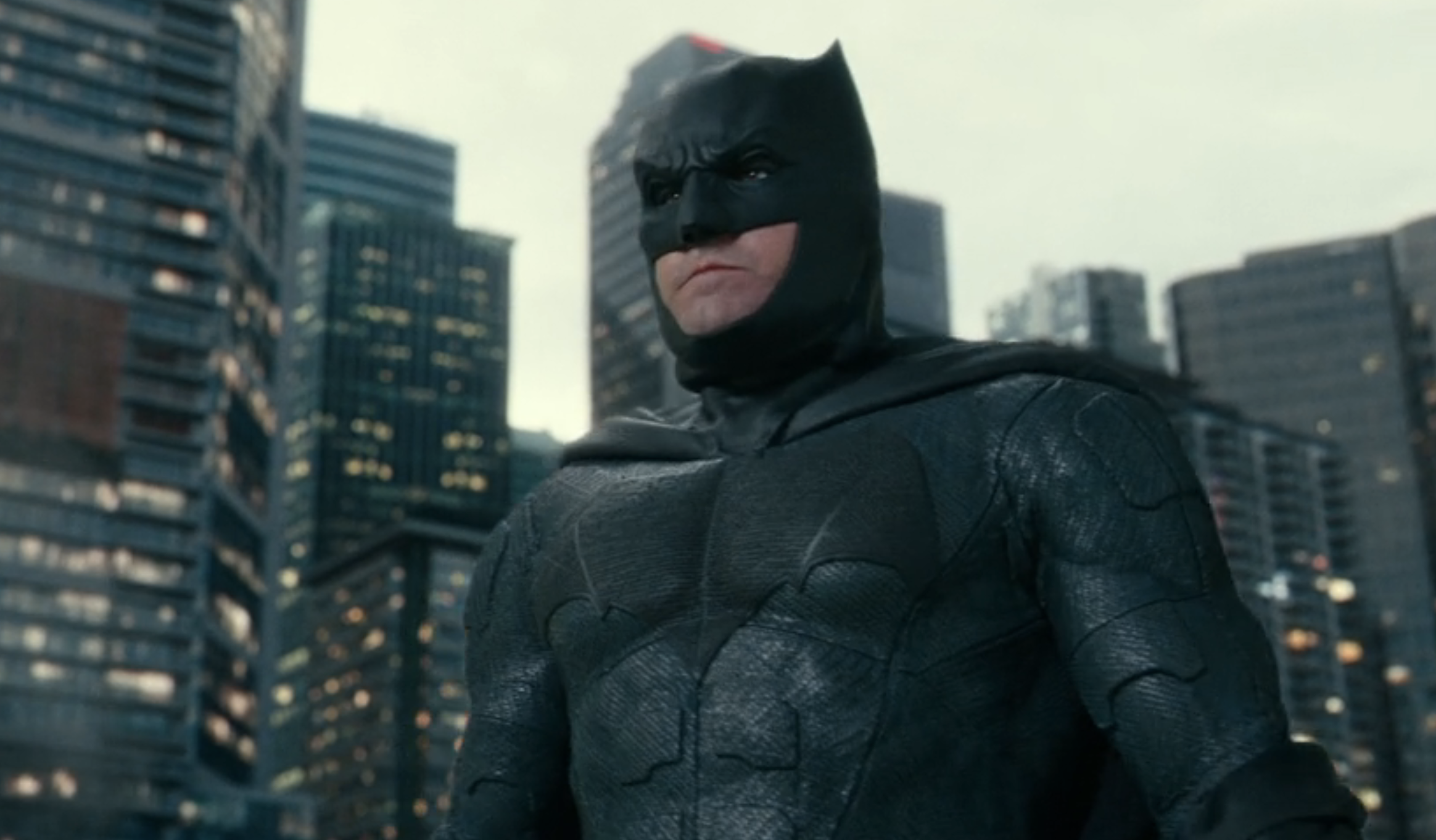 A closeup of Ben Affleck of Batman with a city backdrop