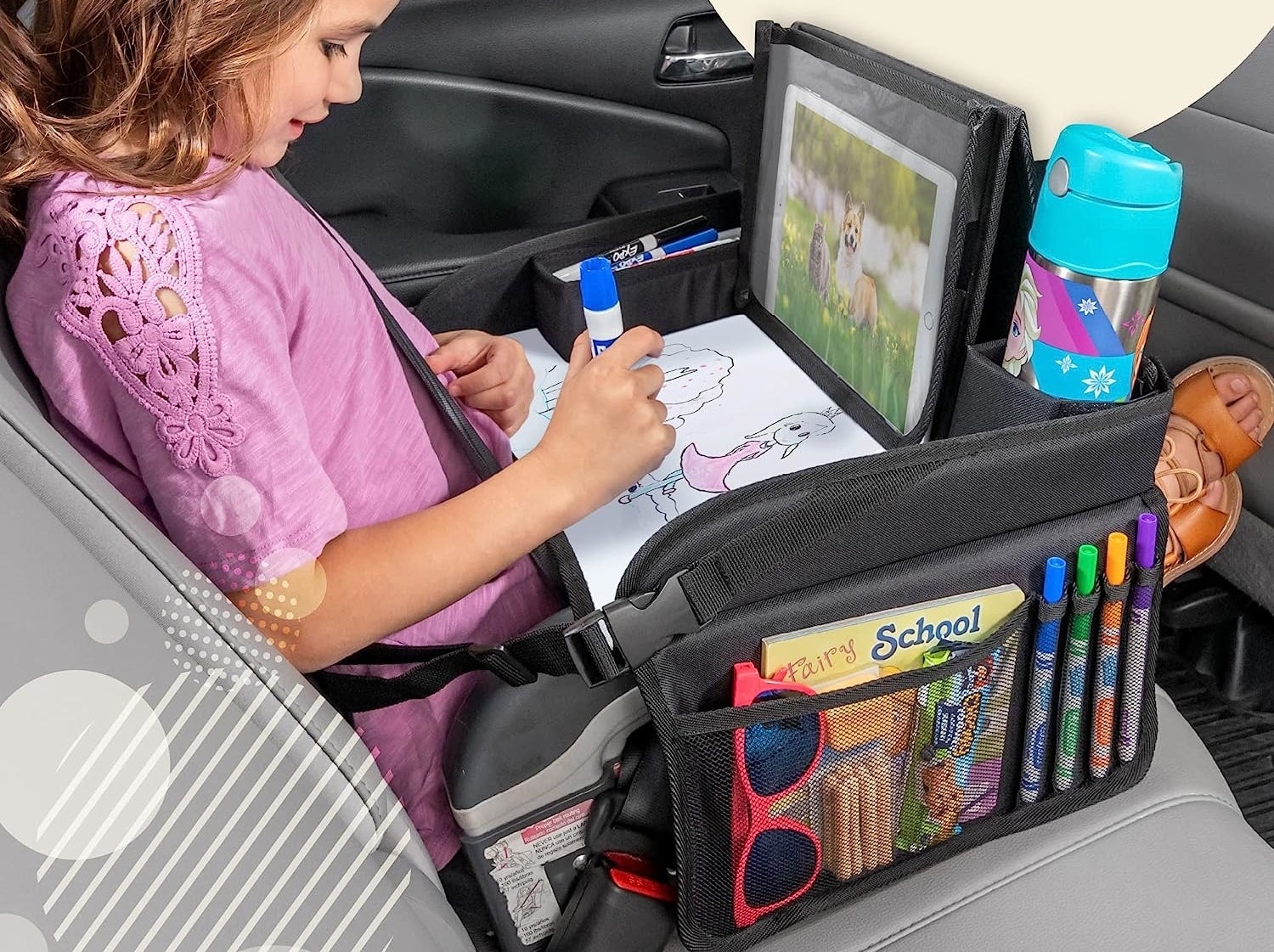 Child model sitting in car drawing with black travel tray on lap