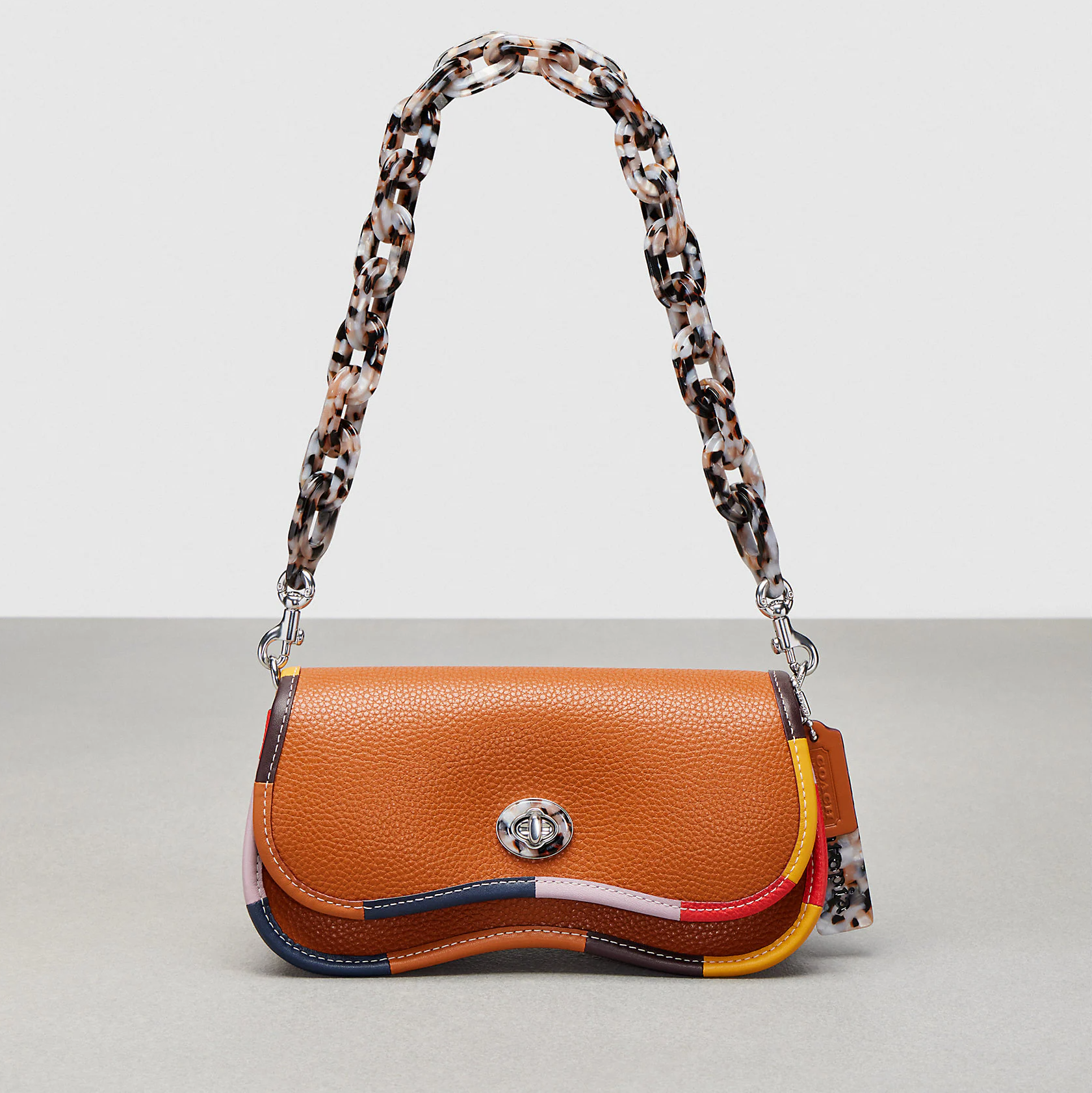 A Coachtopia bag made out of recycled materials in brown with a multicolored strap chain.