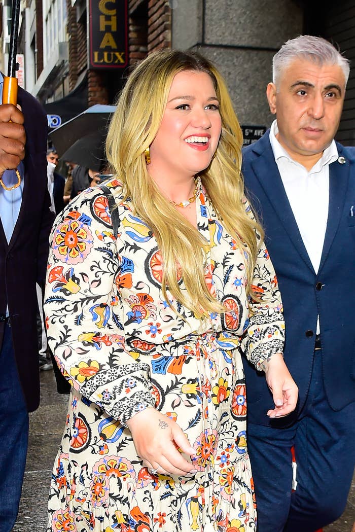 Kelly Clarkson smiles as she walks outside in a floral-print dress