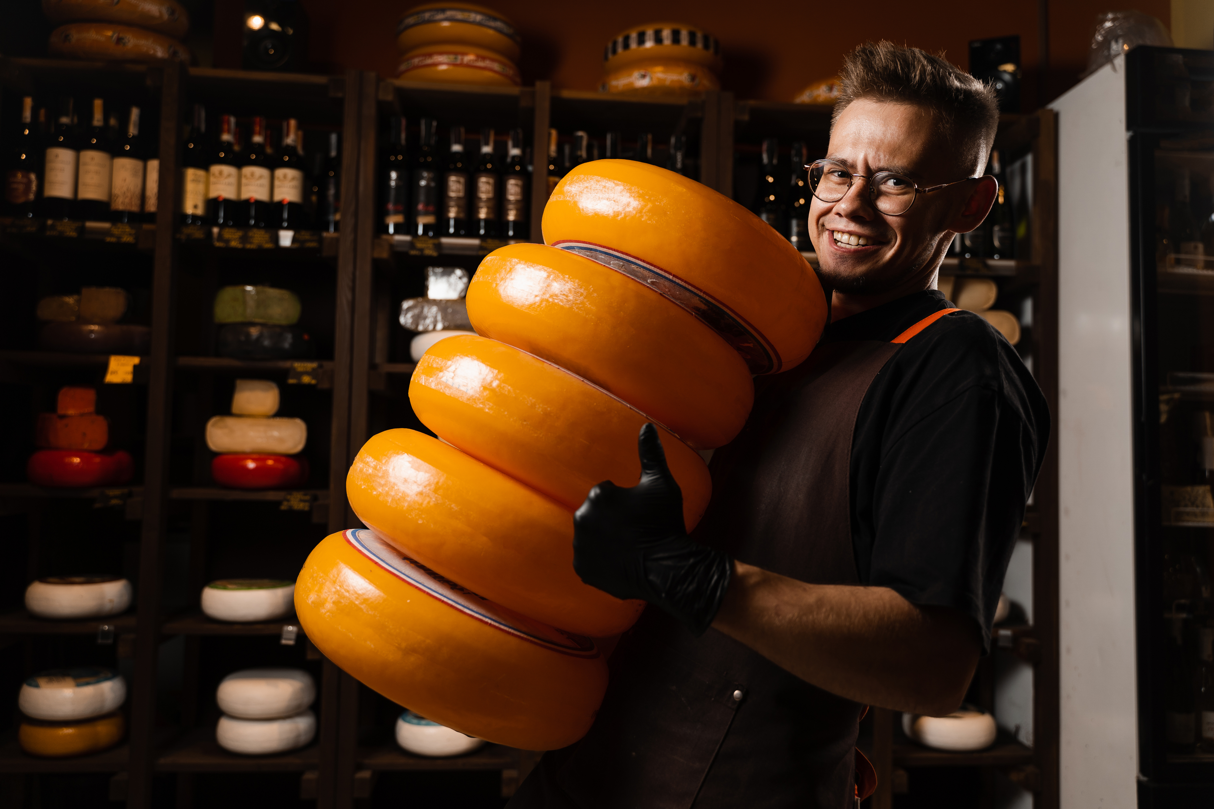 A person holding huge wheels of Brie