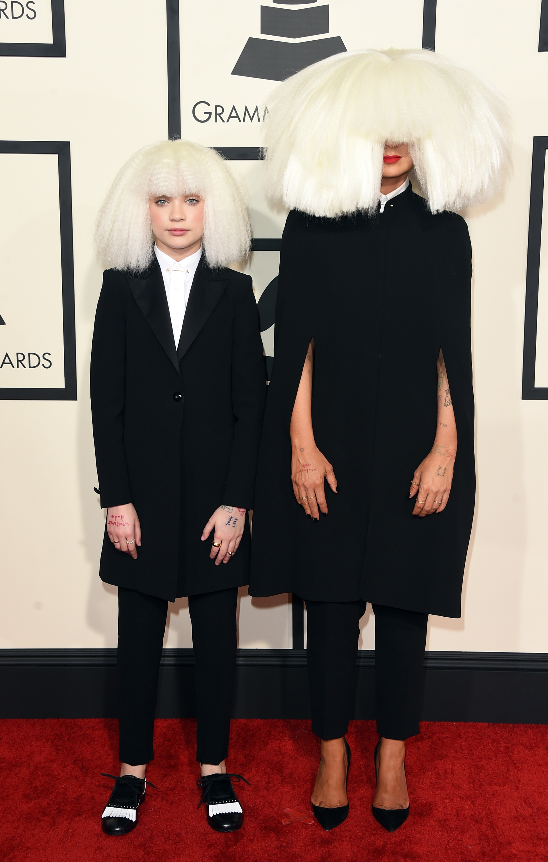 Maddie and Sia pose together on the red carpet in matching jackets, pencil pants, and hair