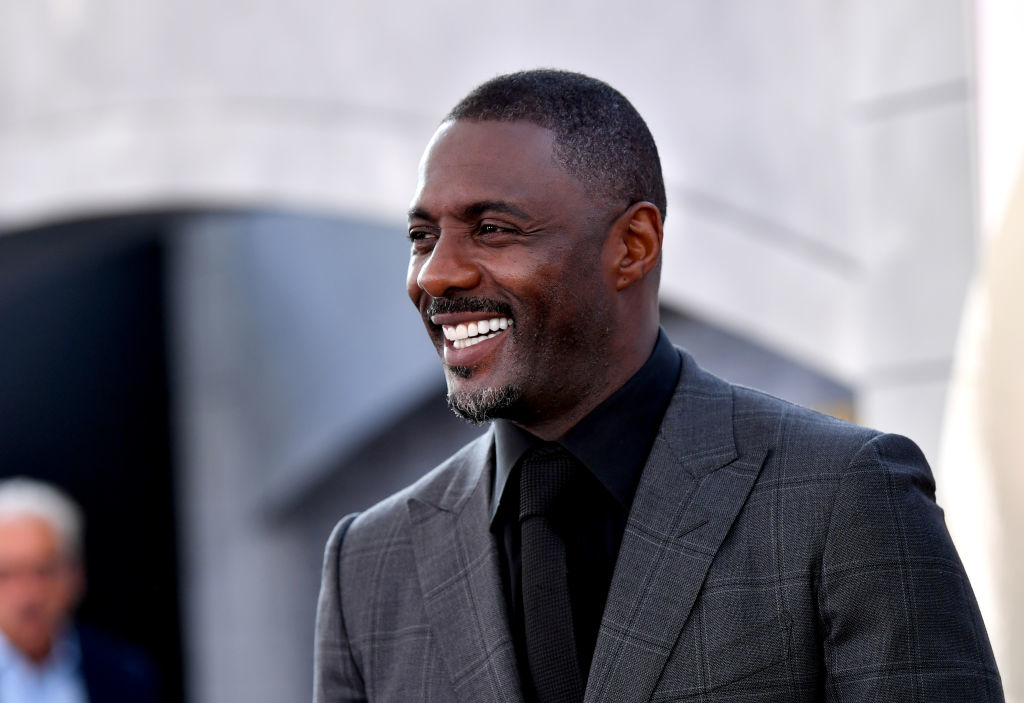 Close-up of Idris smiling in a suit and tie