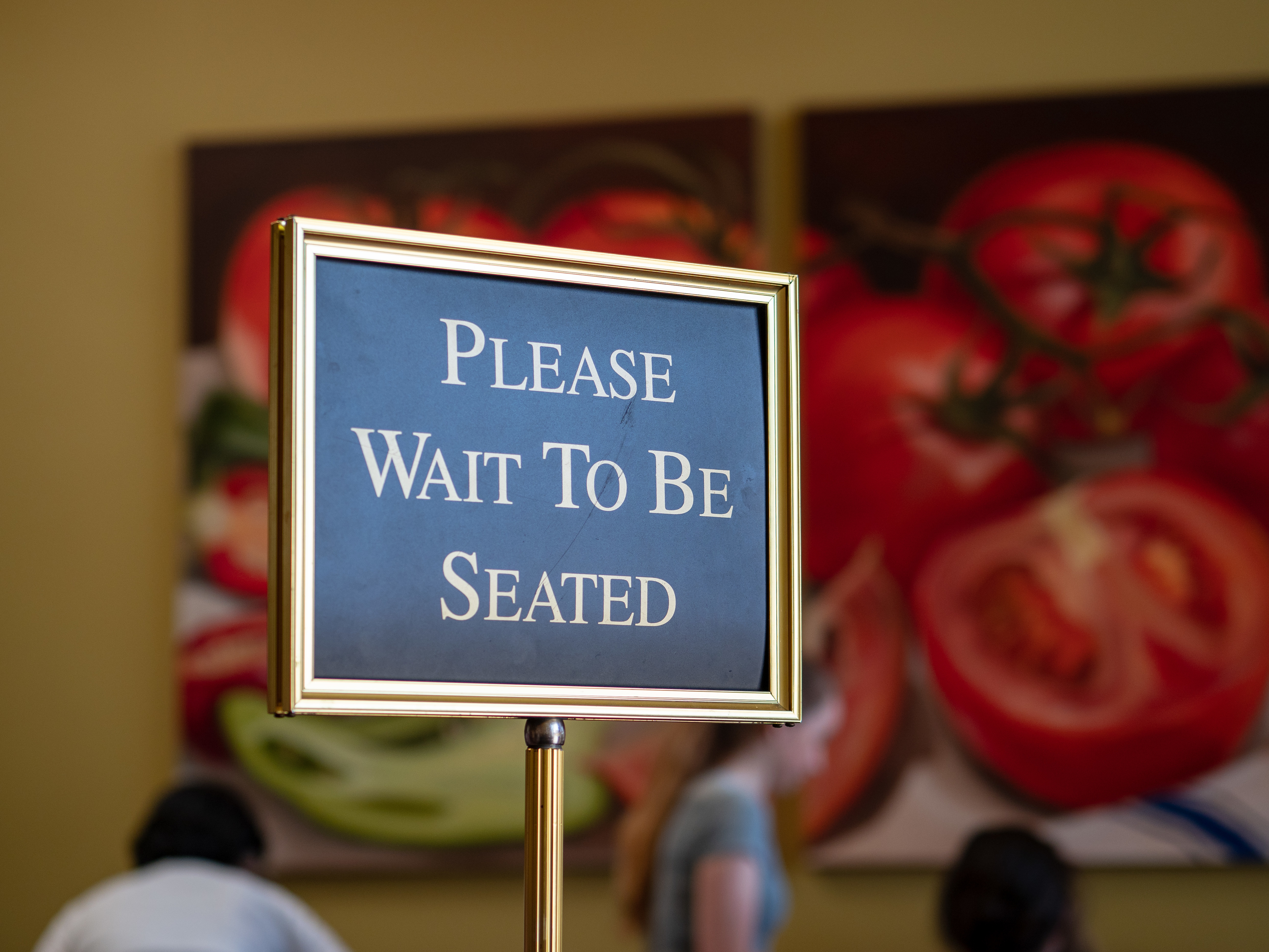 Close-up of &quot;Please wait to be seated&quot; sign