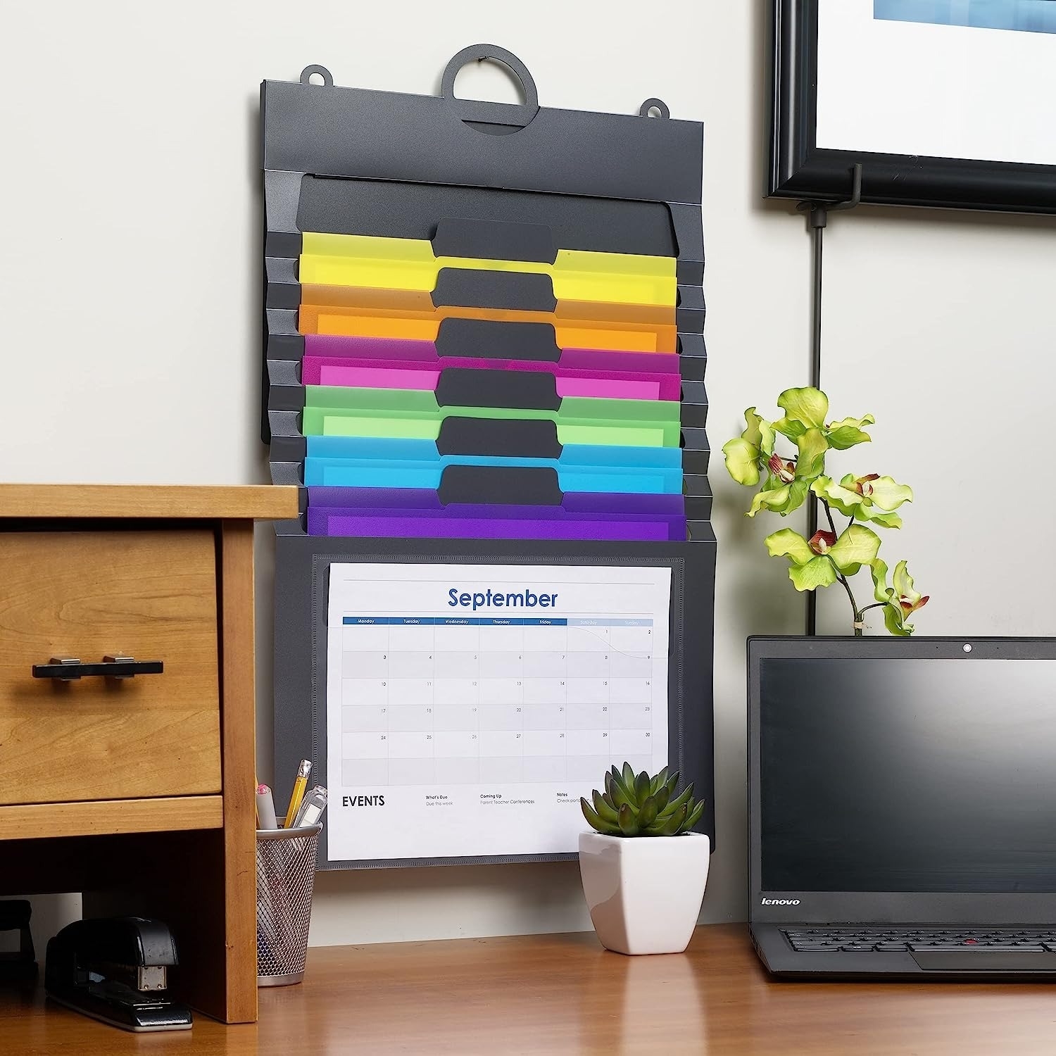 A wall organizer hung up by a desk.